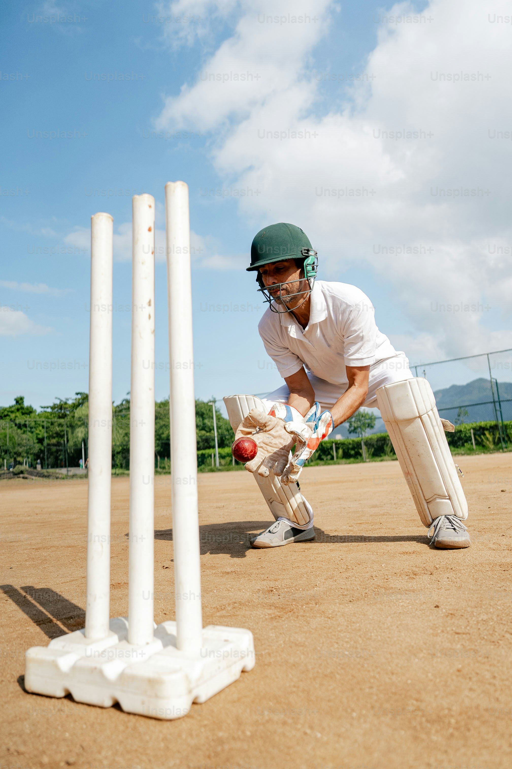 A man playing a game of cricket on a dirt field photo – Sport Image on ...