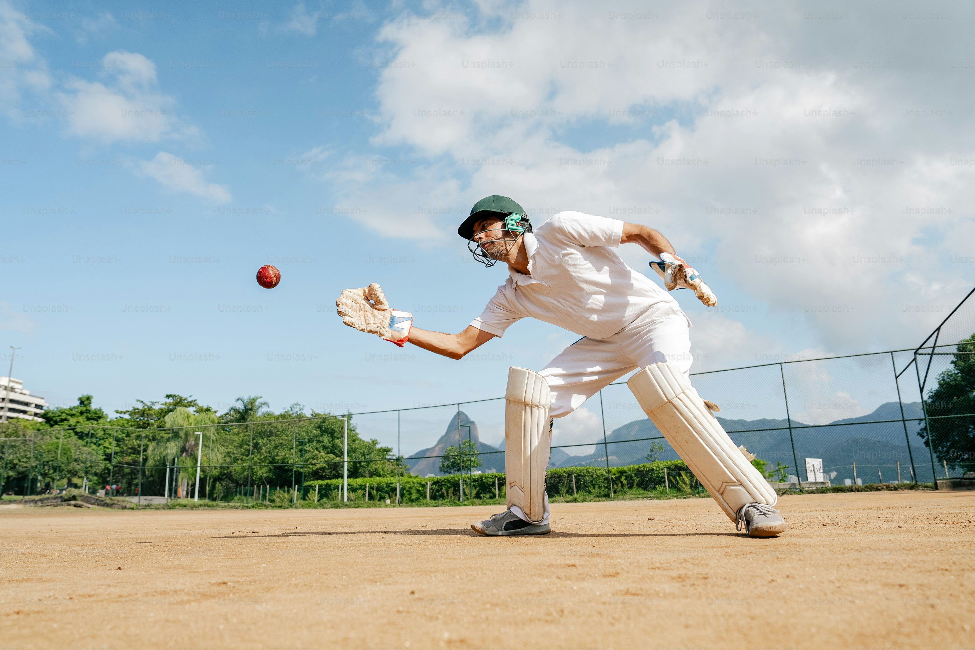 A man playing a game of cricket on a dirt field