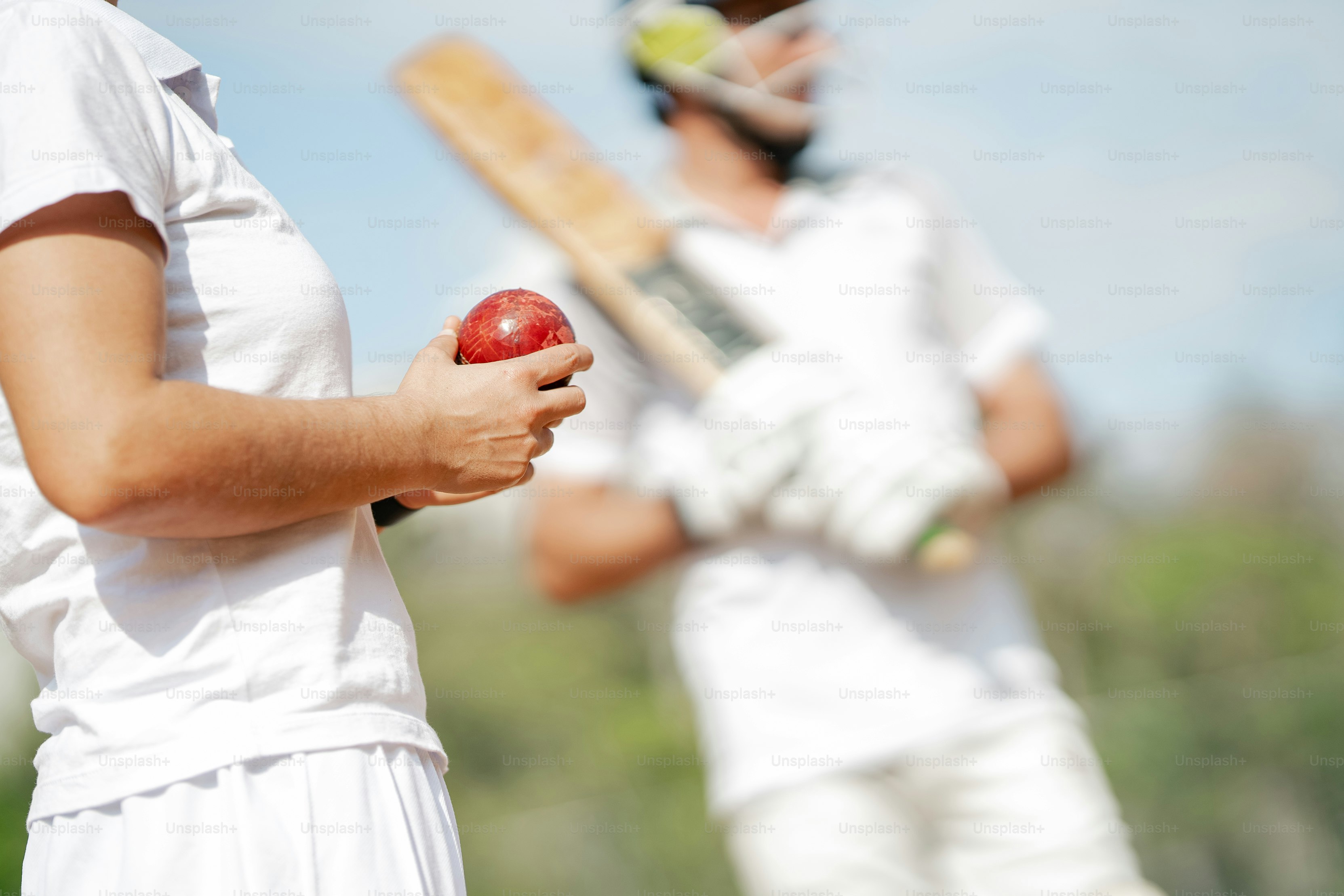 A man and a woman holding a red ball and a bat