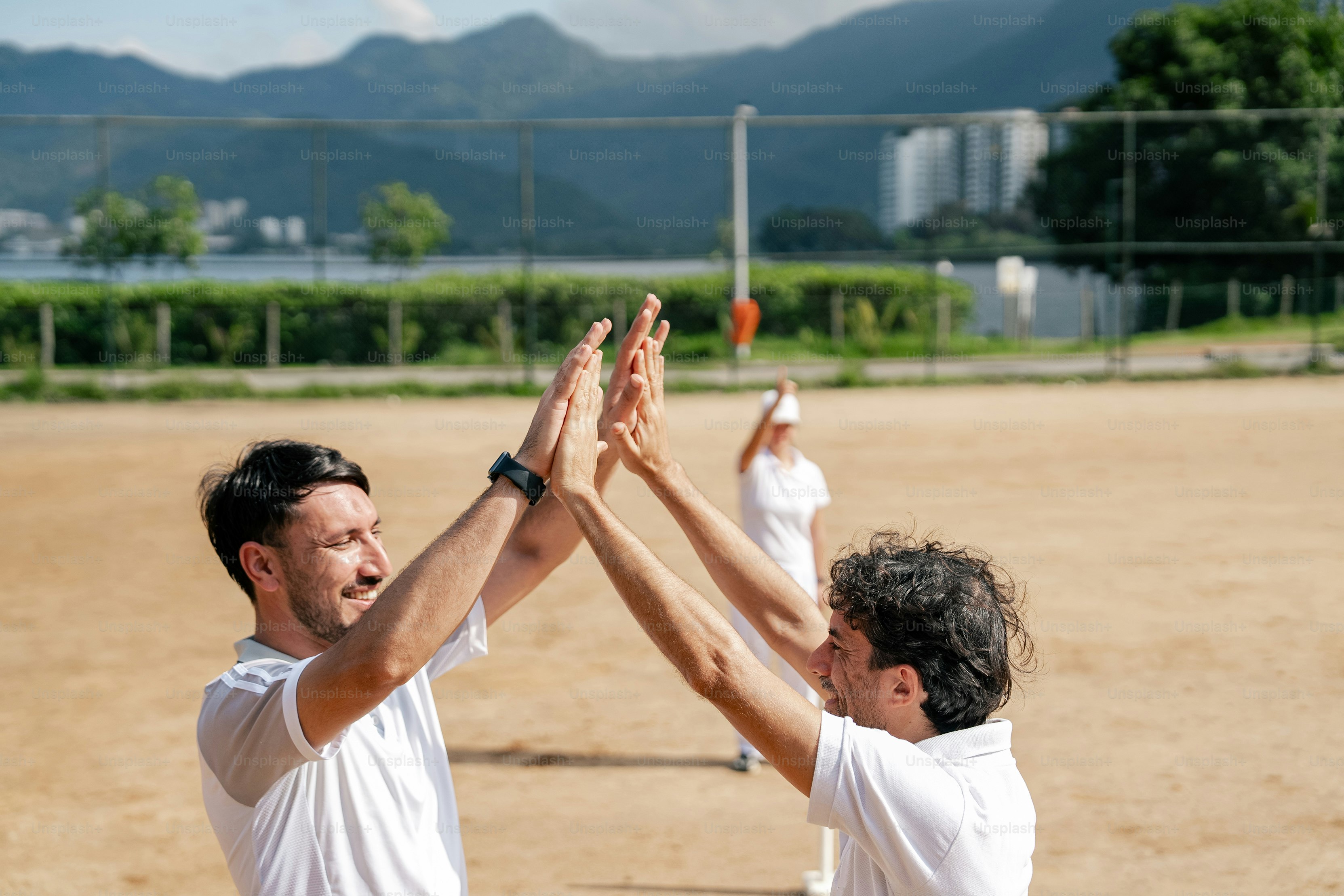 A couple of men standing on top of a dirt field