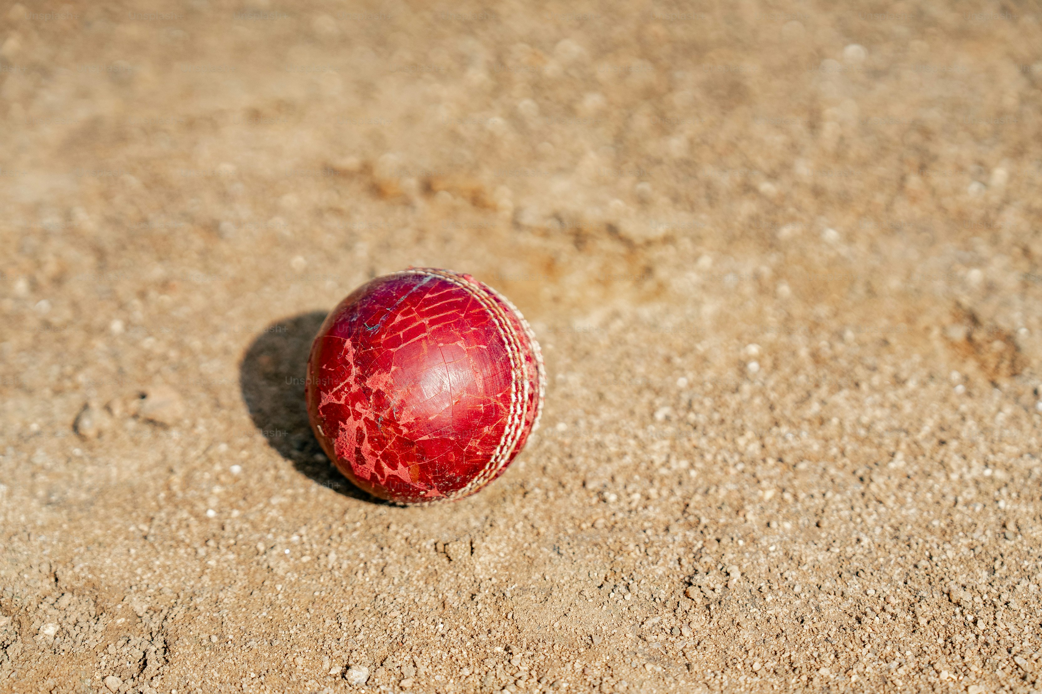 A red cricket ball laying on the ground
