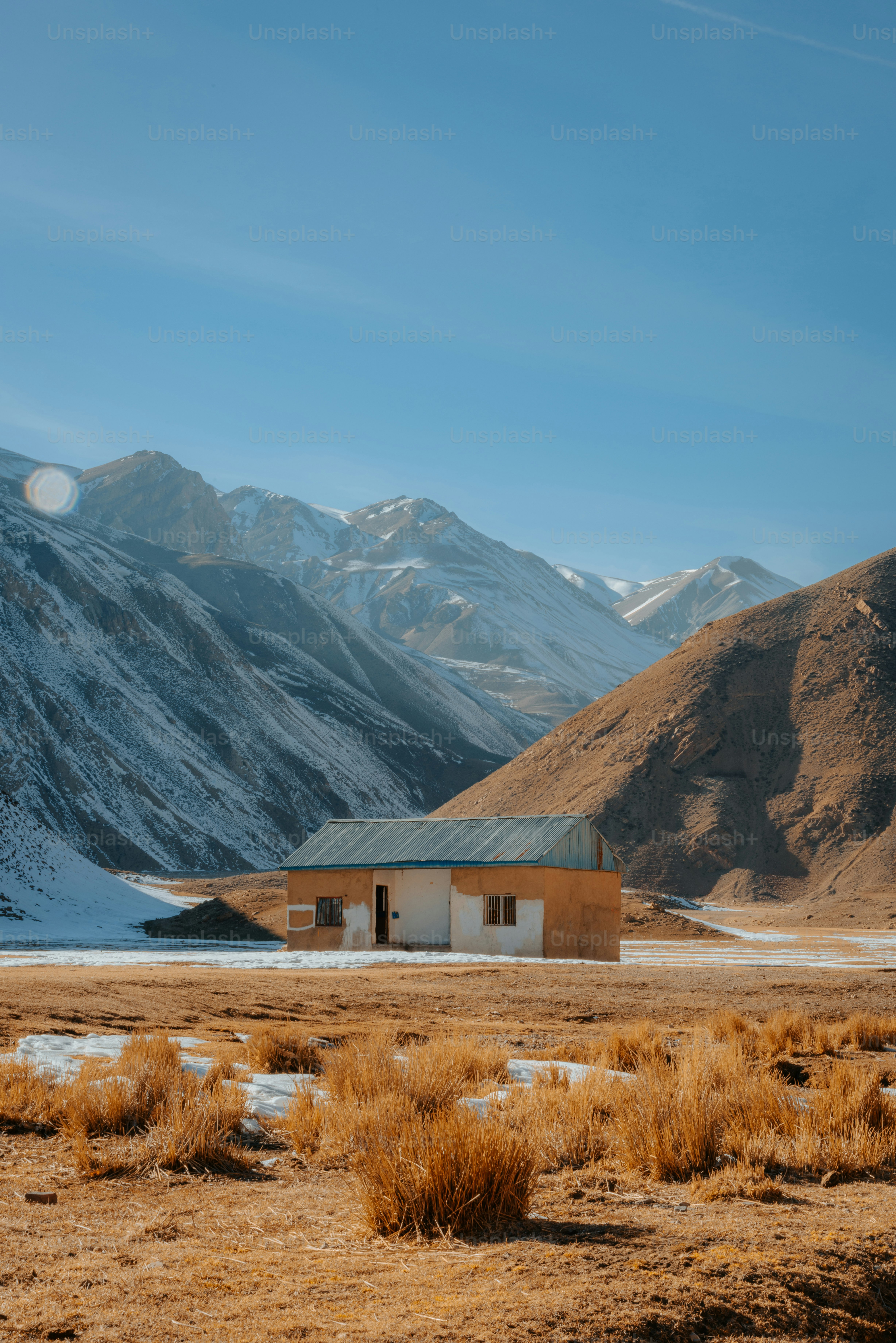A house in the middle of a field with mountains in the background