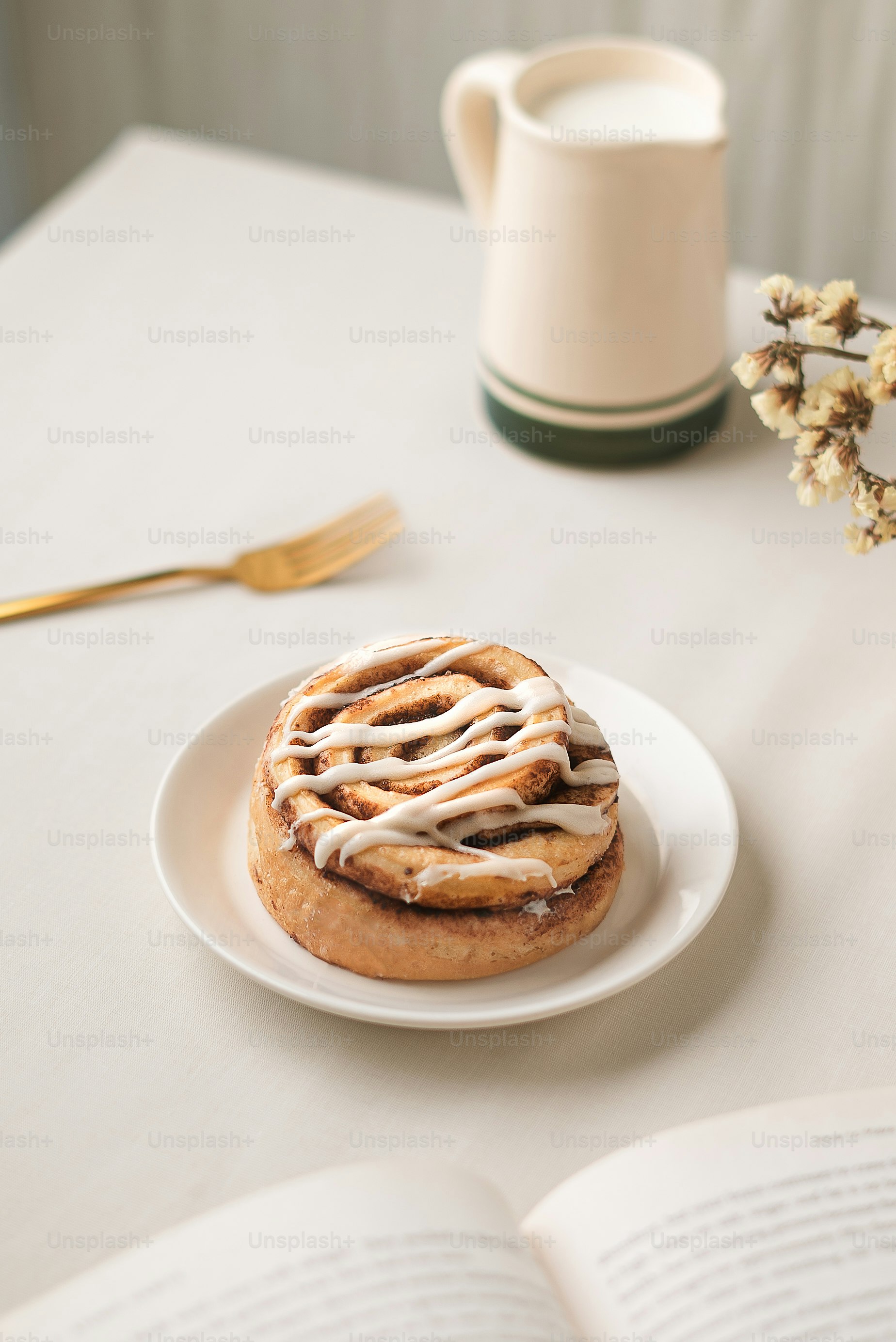 A plate with a cinnamon roll on it next to a cup of coffee