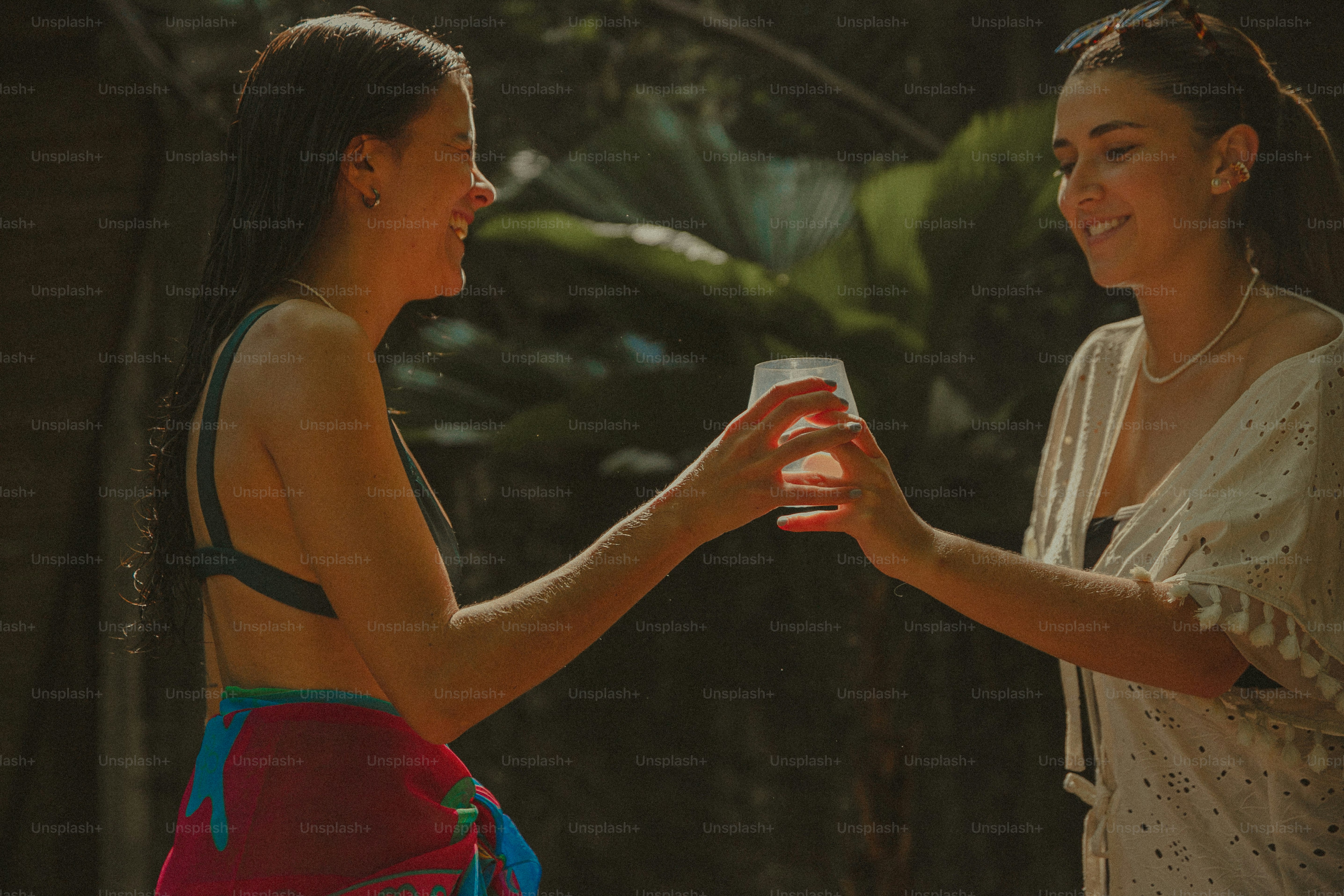 Two women standing next to each other holding drinks