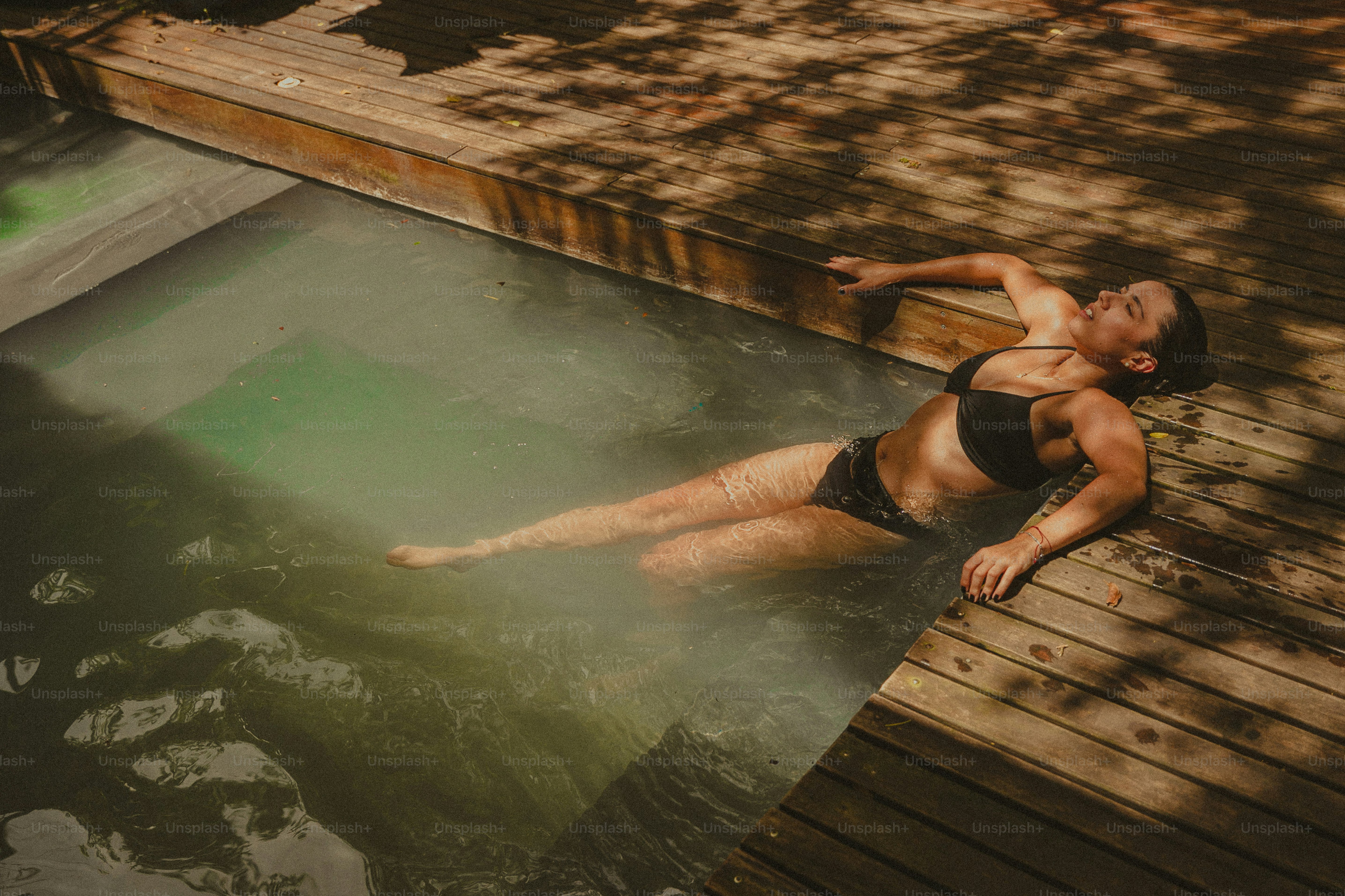 A man in a black swimsuit floating in a pool