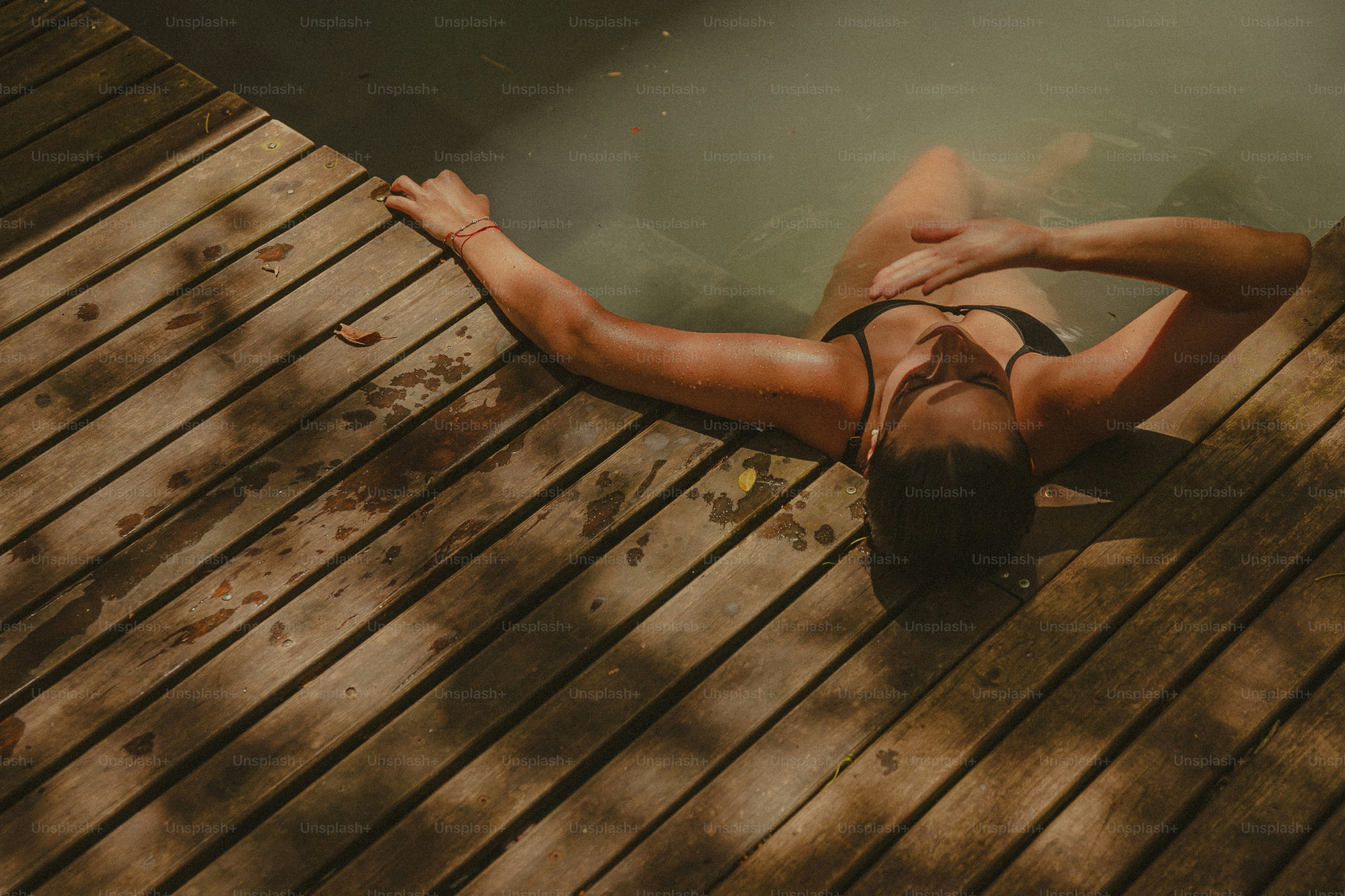 A woman laying on a wooden dock next to a body of water