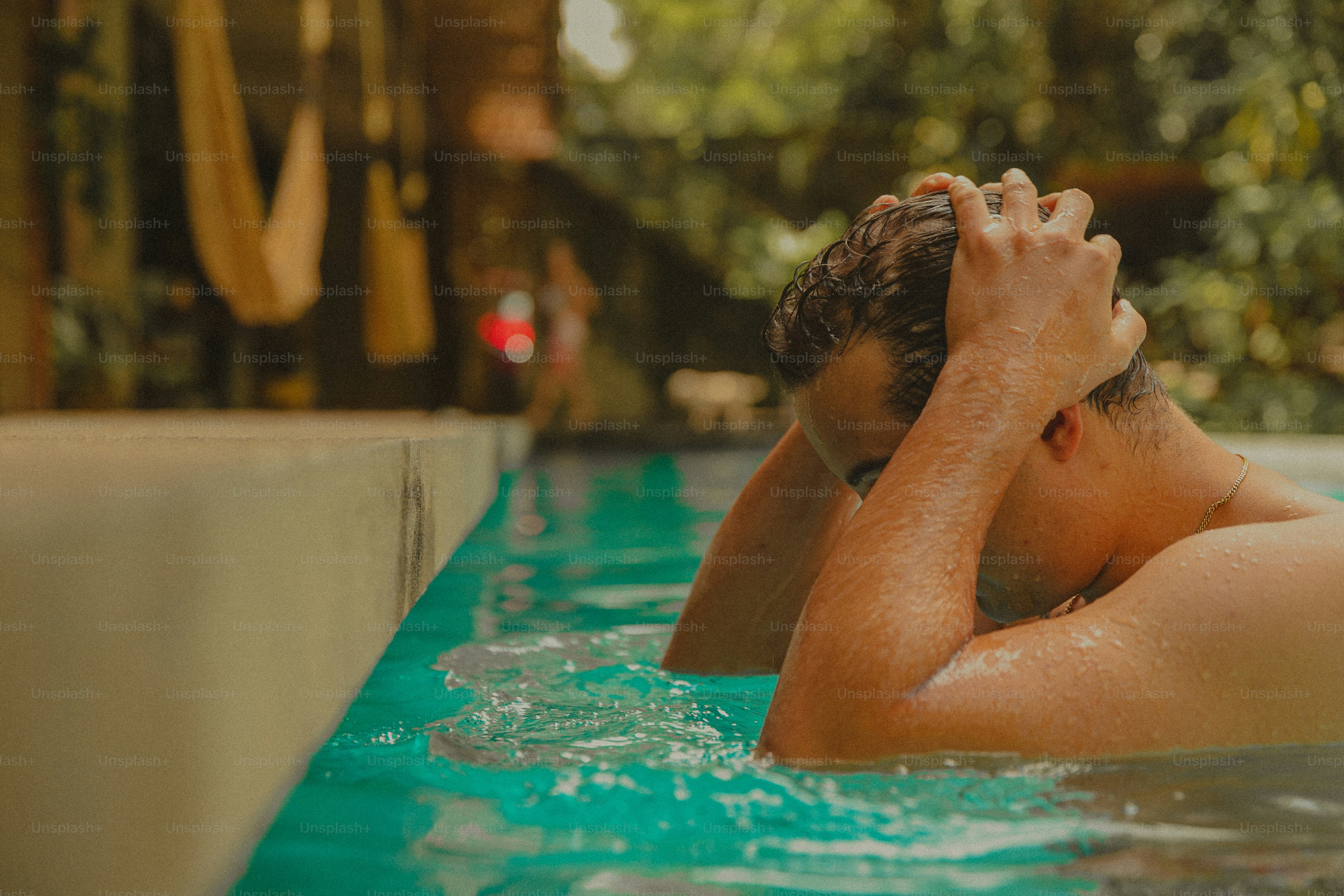 A man in a swimming pool with his head in his hands