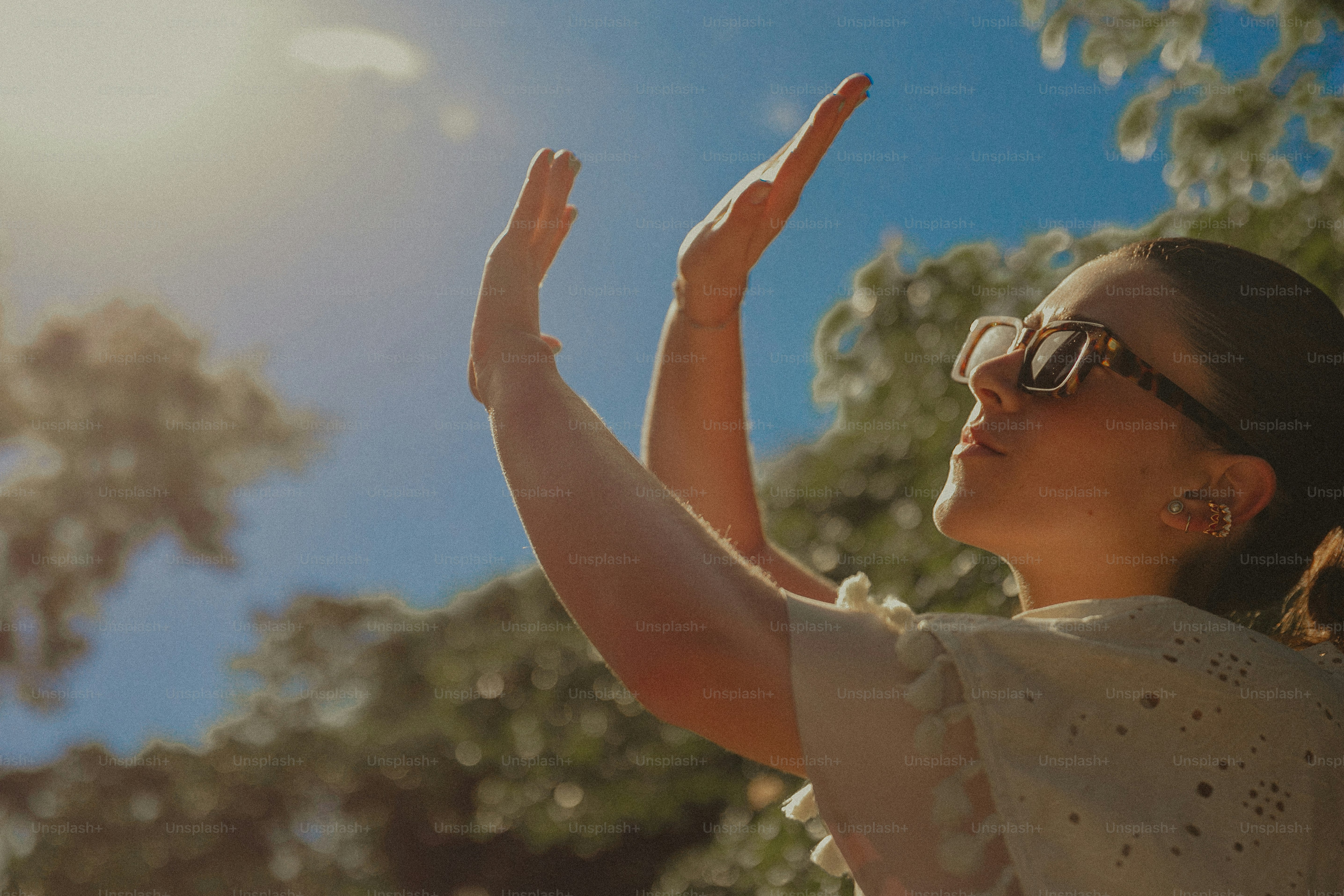 A woman in a white top is reaching up to the sky