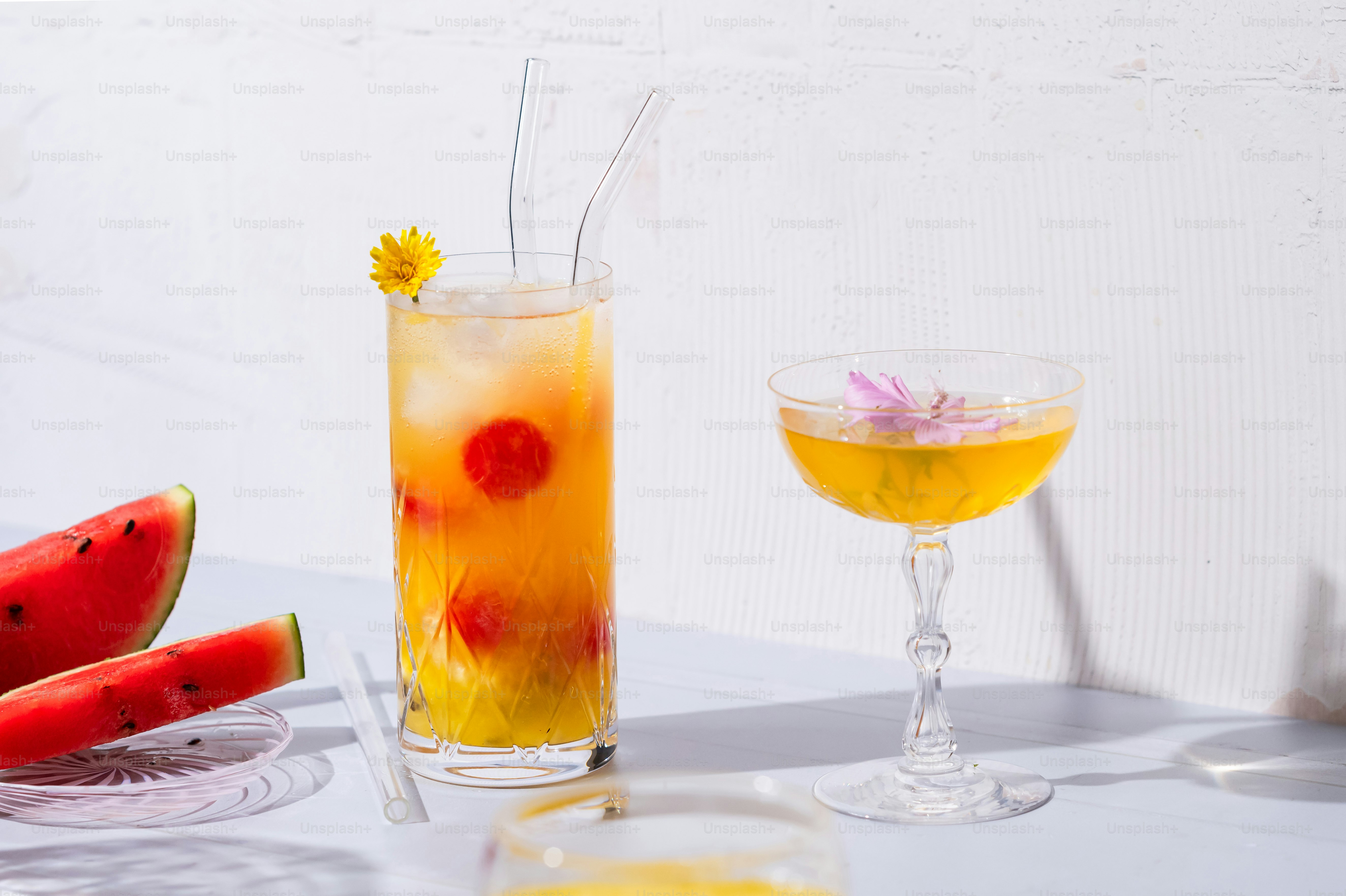 A glass of watermelon juice next to a glass of watermelon juice