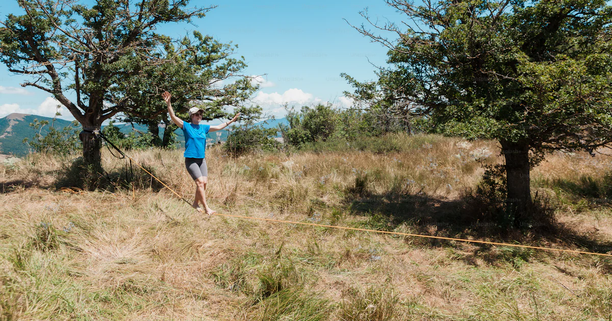 A man standing on top of a grass covered field photo – Slackline Image ...