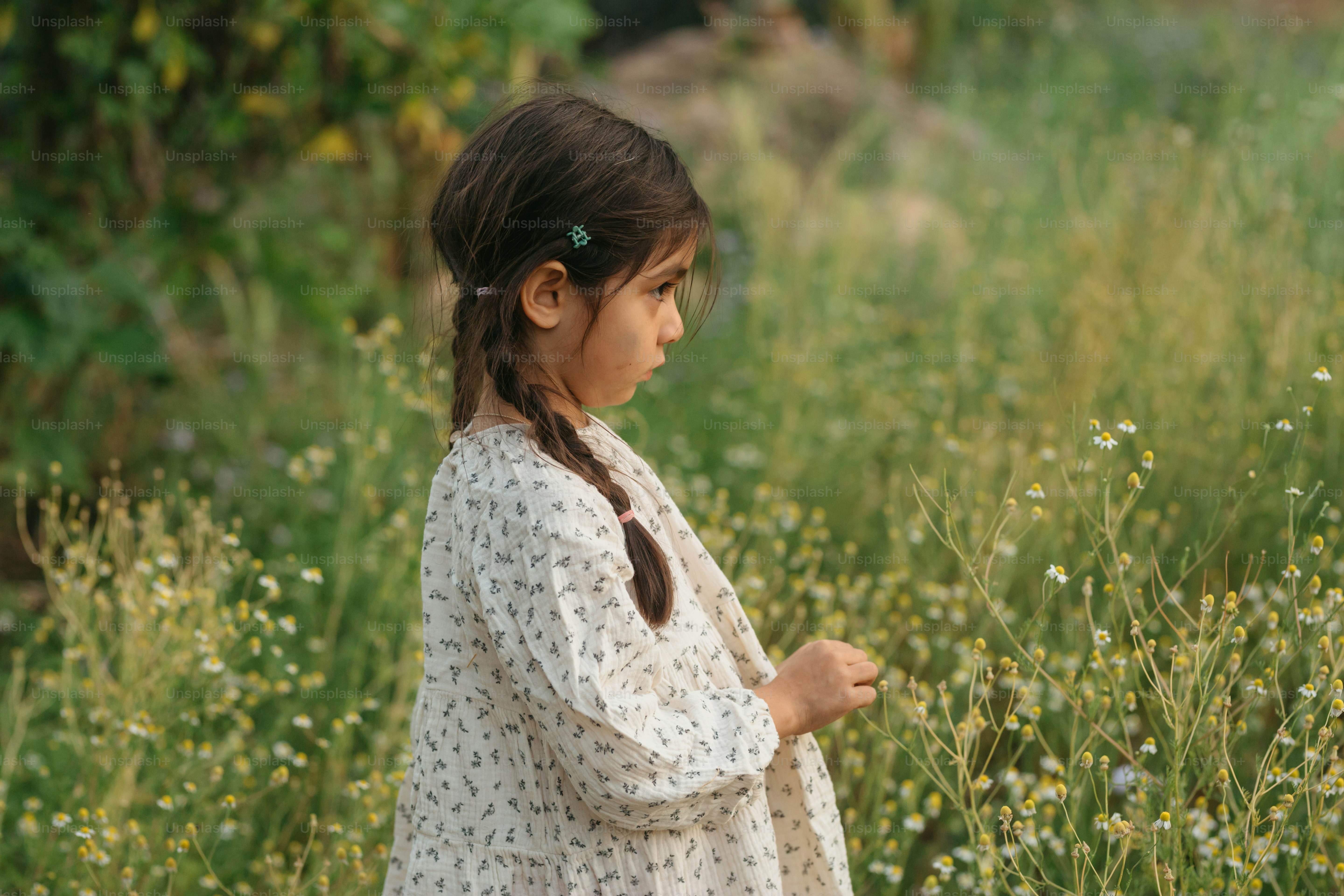 A little girl standing in a field of flowers photo – Family Image on ...