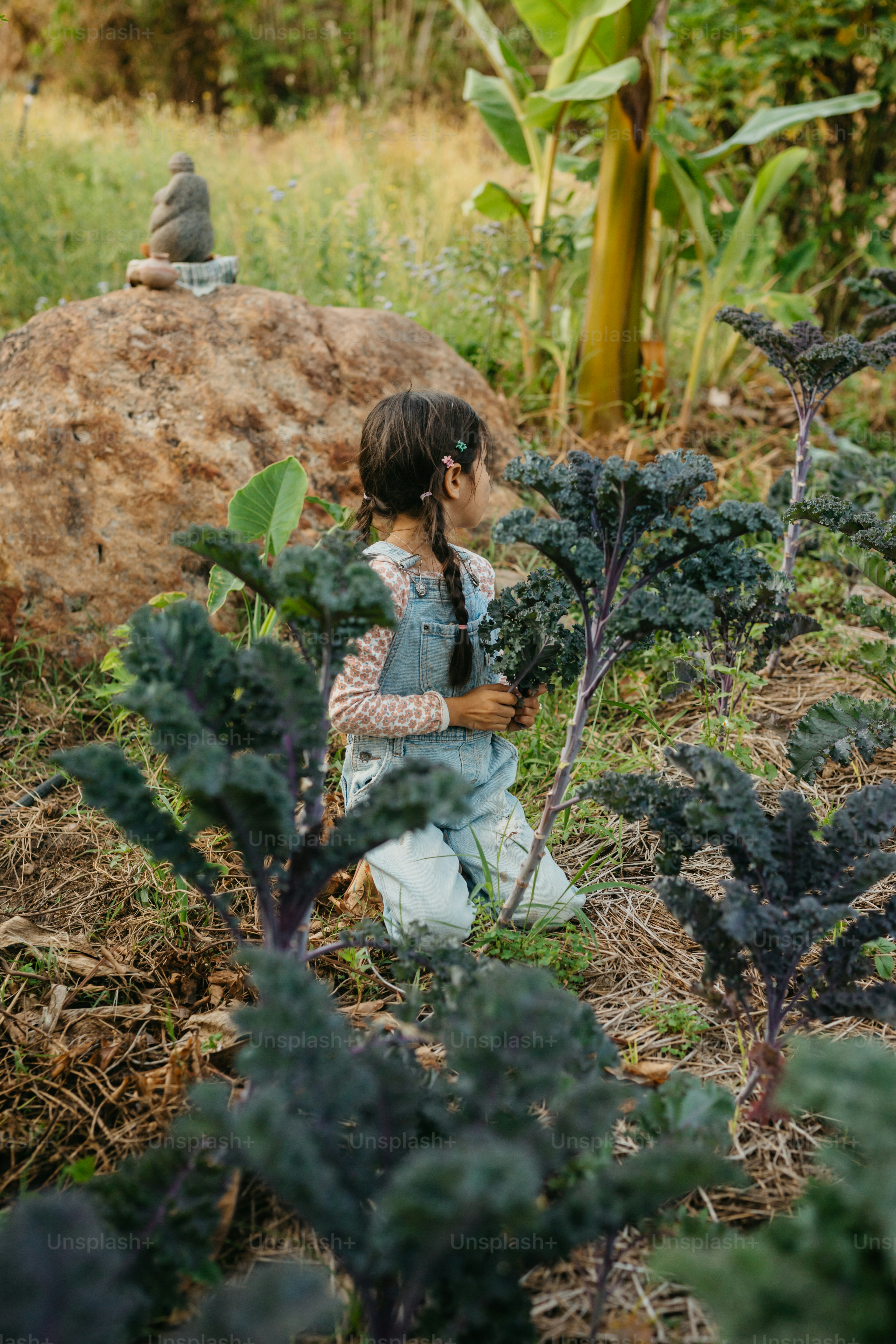 Una bambina in piedi in un campo di verdure