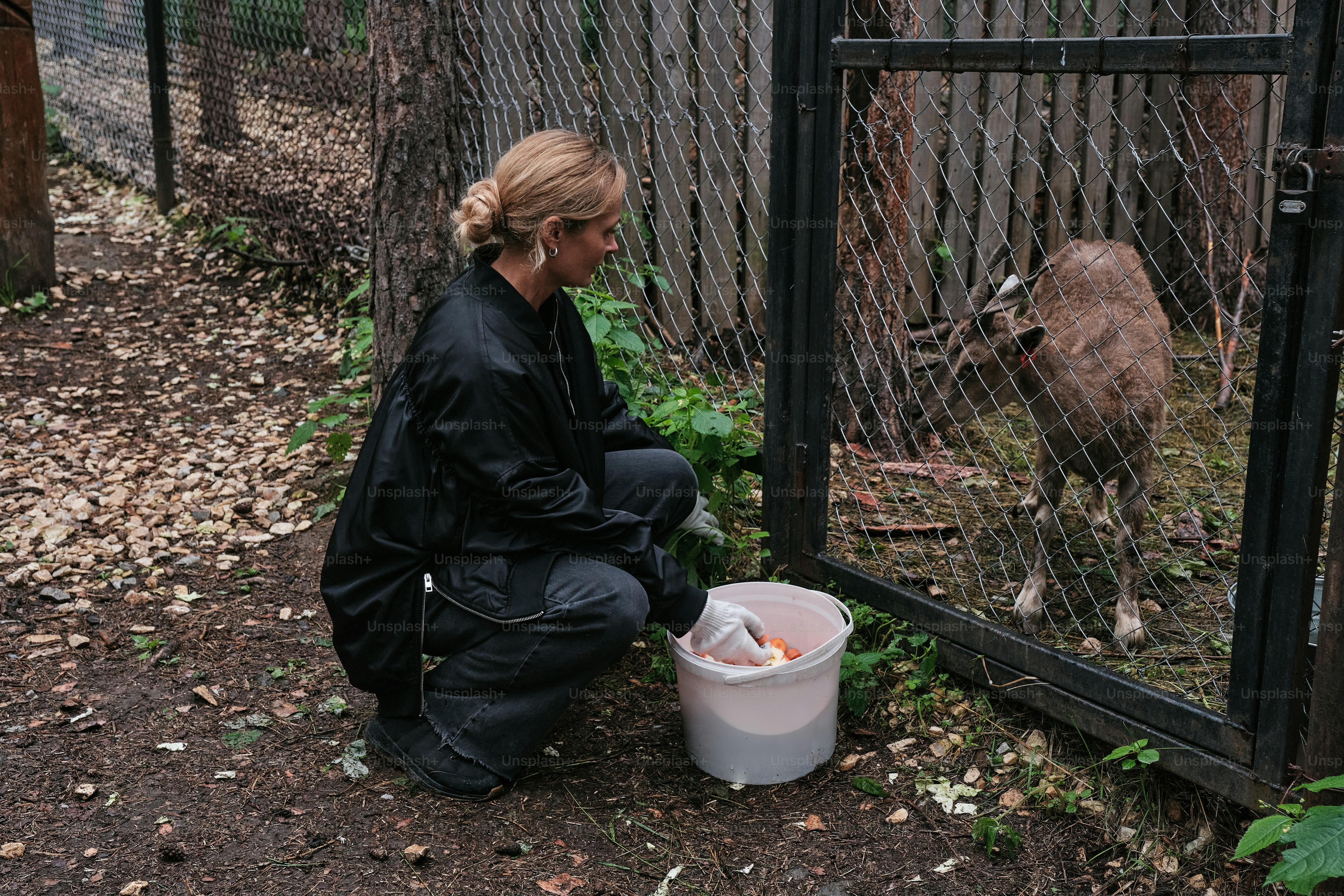 A woman sitting on the ground next to a fence
