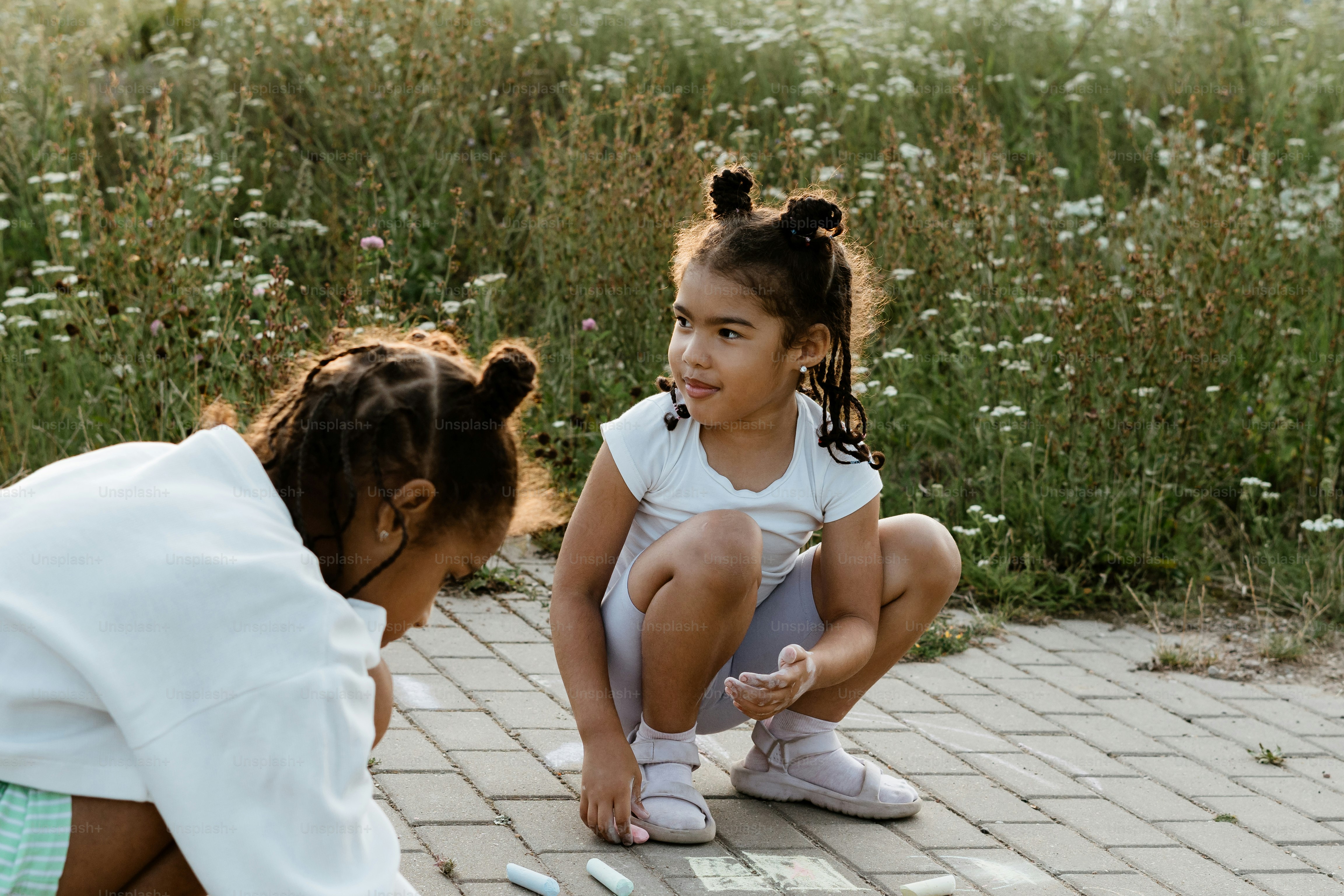 A woman kneeling down next to a little girl