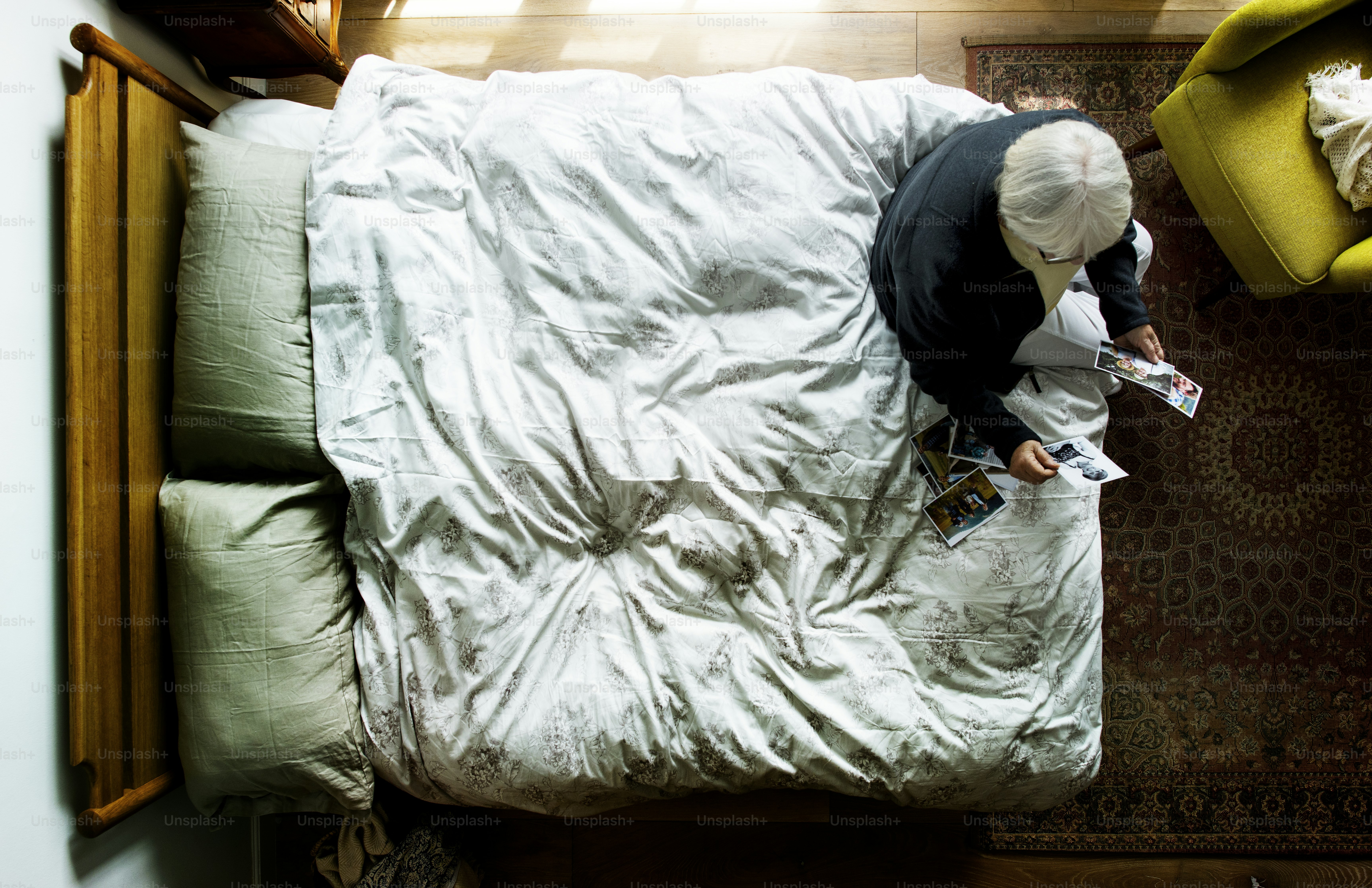 Elderly Caucasian sitting on the bed looking at photos