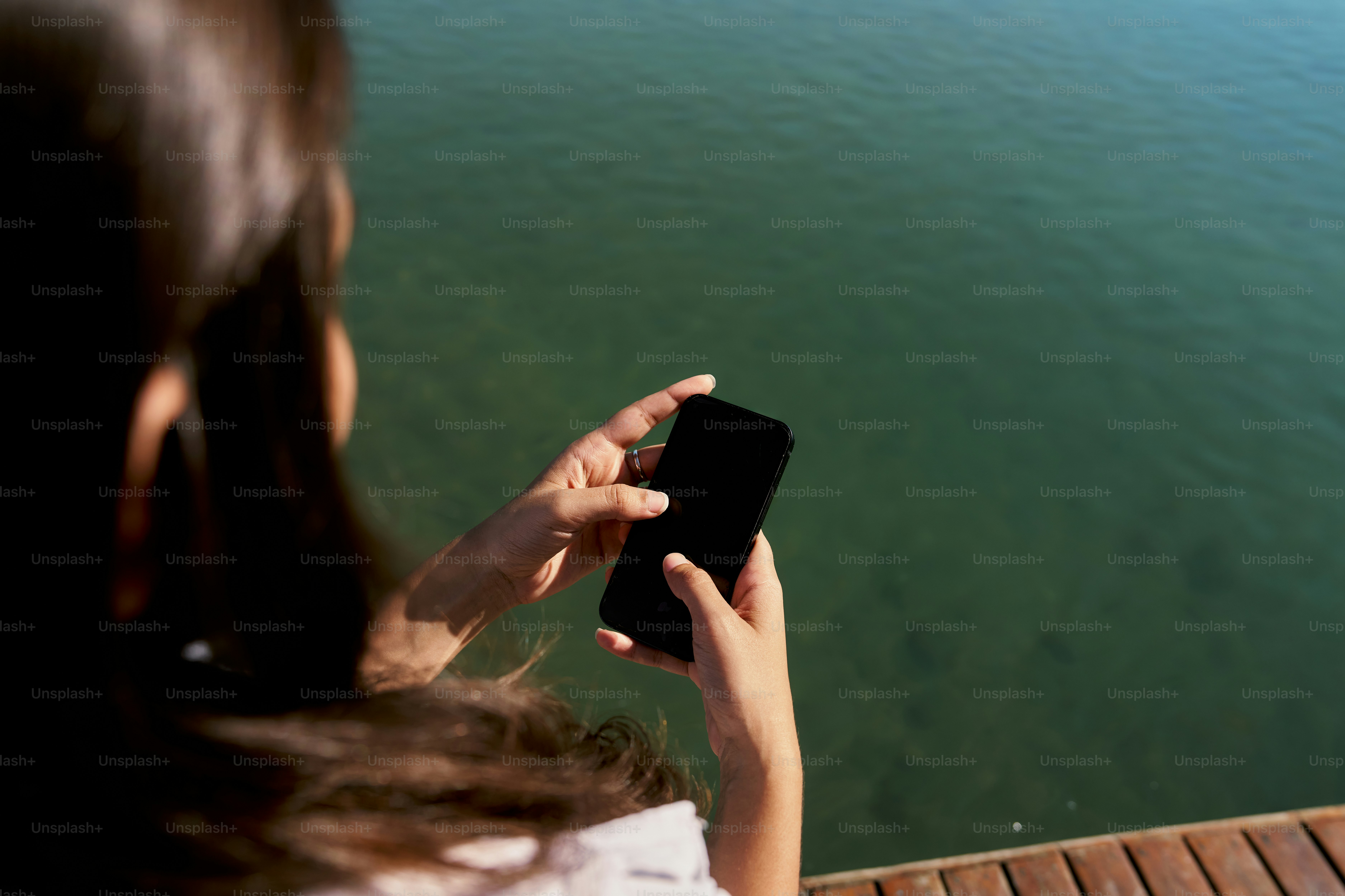 A woman is looking at her cell phone near the water