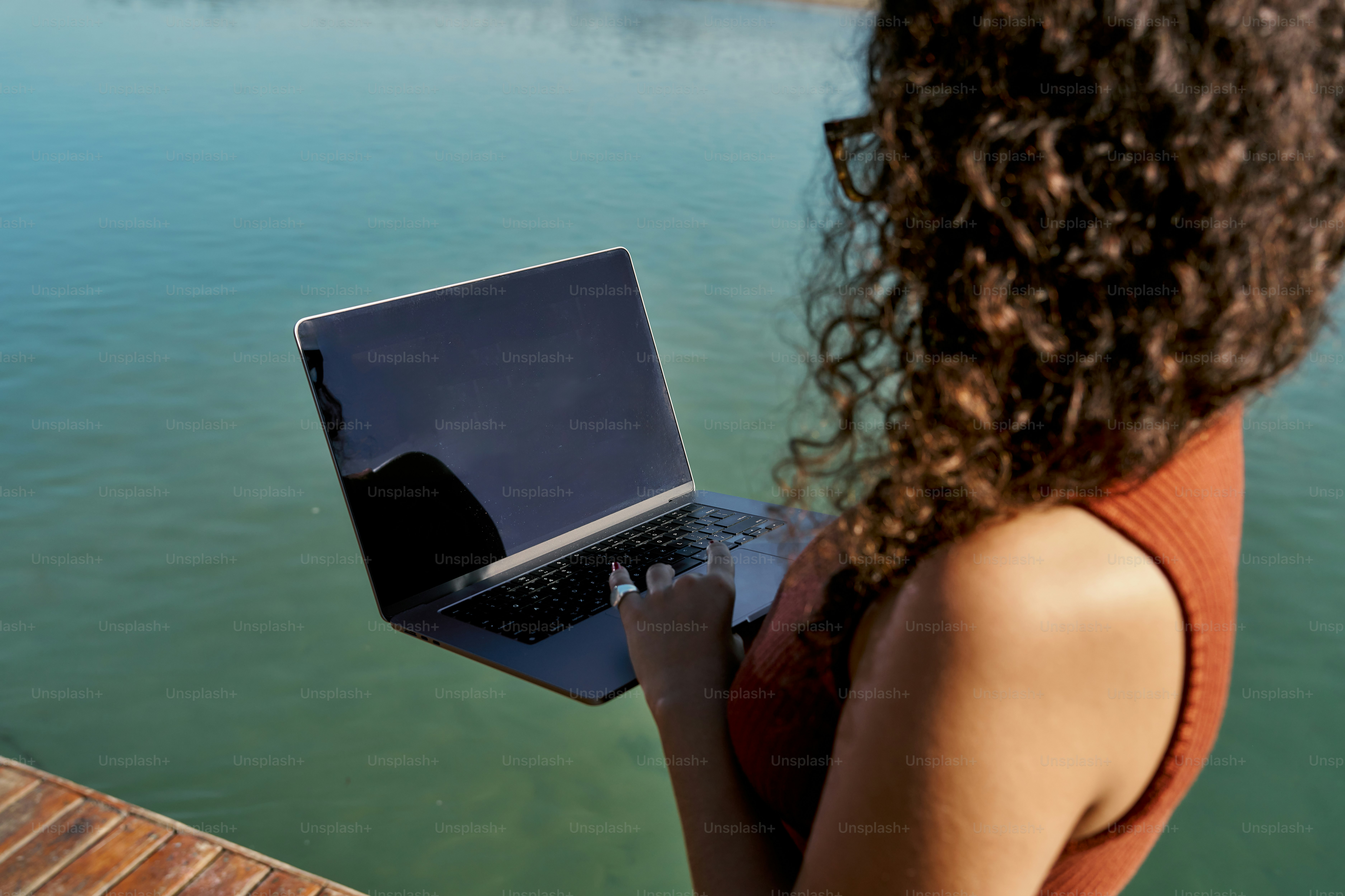 A woman standing on a dock with a laptop in her hand