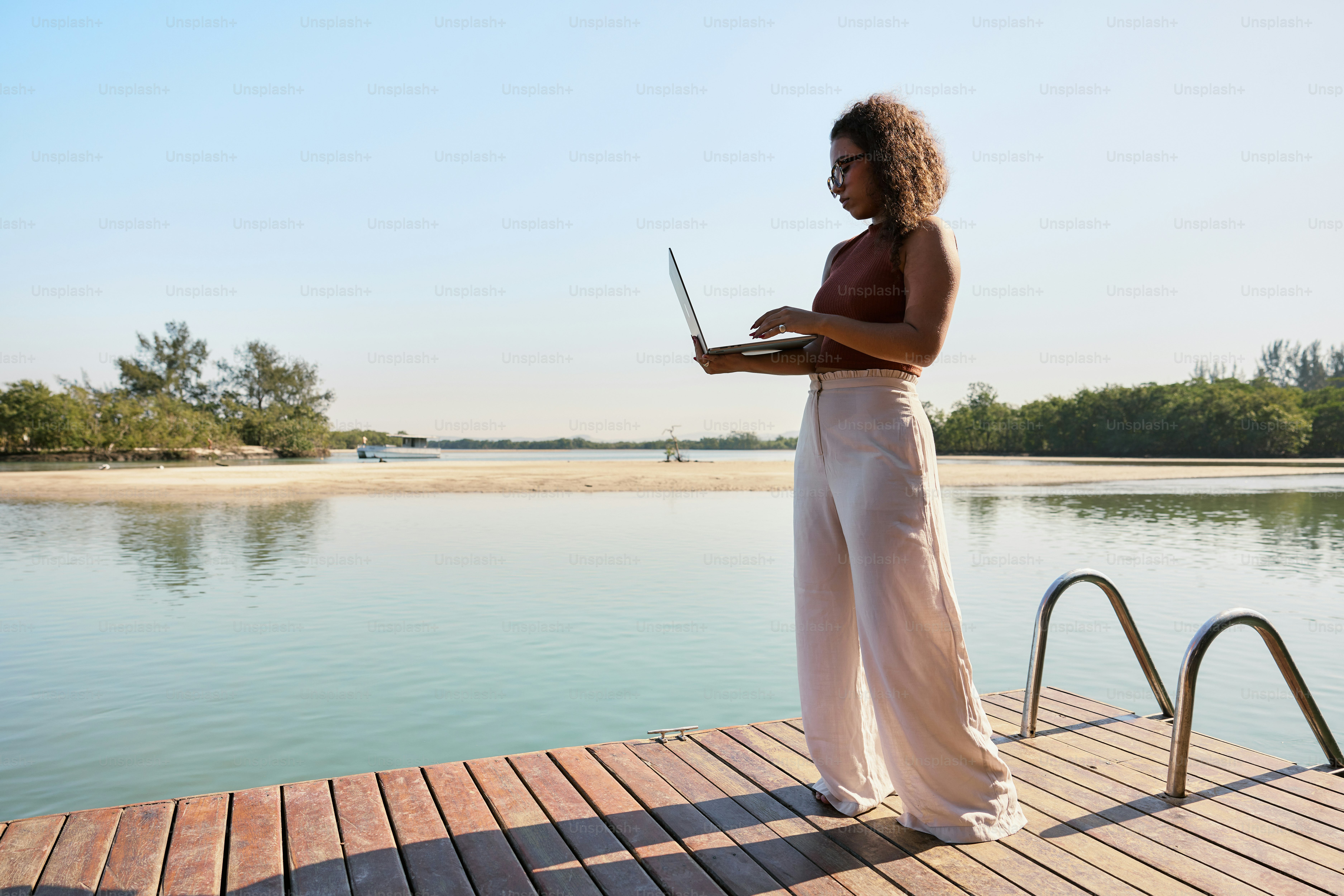 Una mujer de pie en un muelle usando una computadora portátil