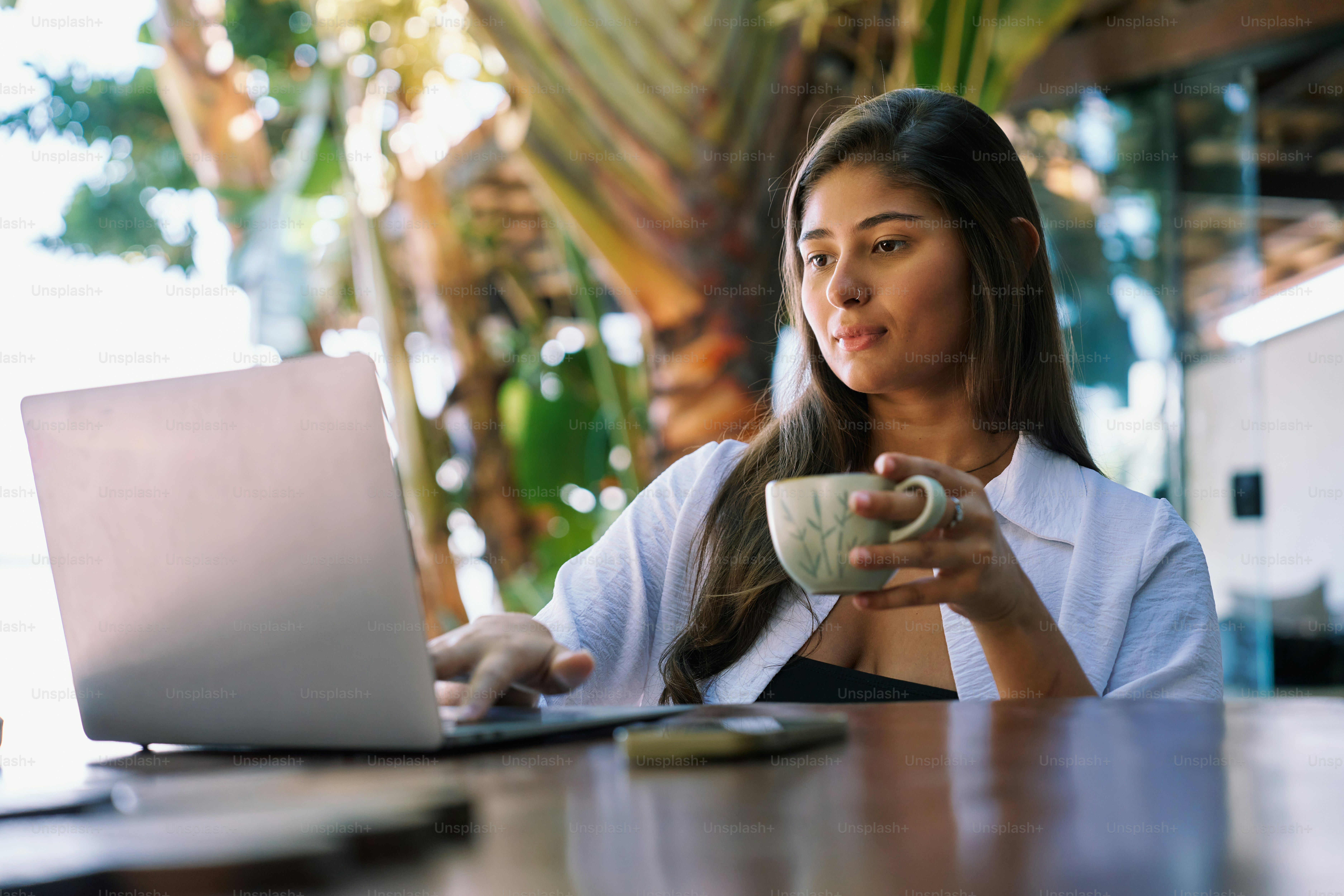 A woman sitting at a table with a laptop and a cup of coffee