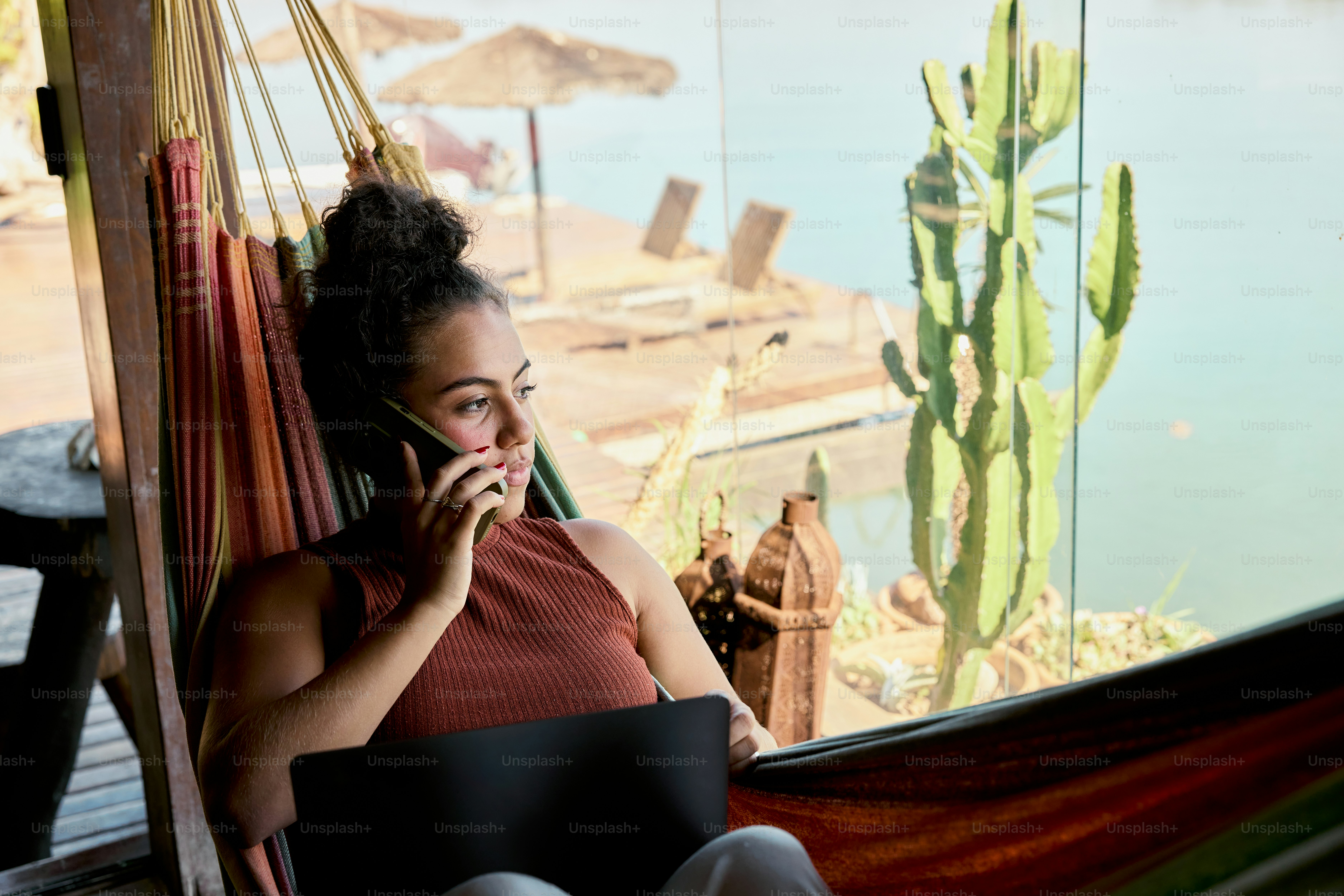 A woman sitting in a hammock talking on a cell phone