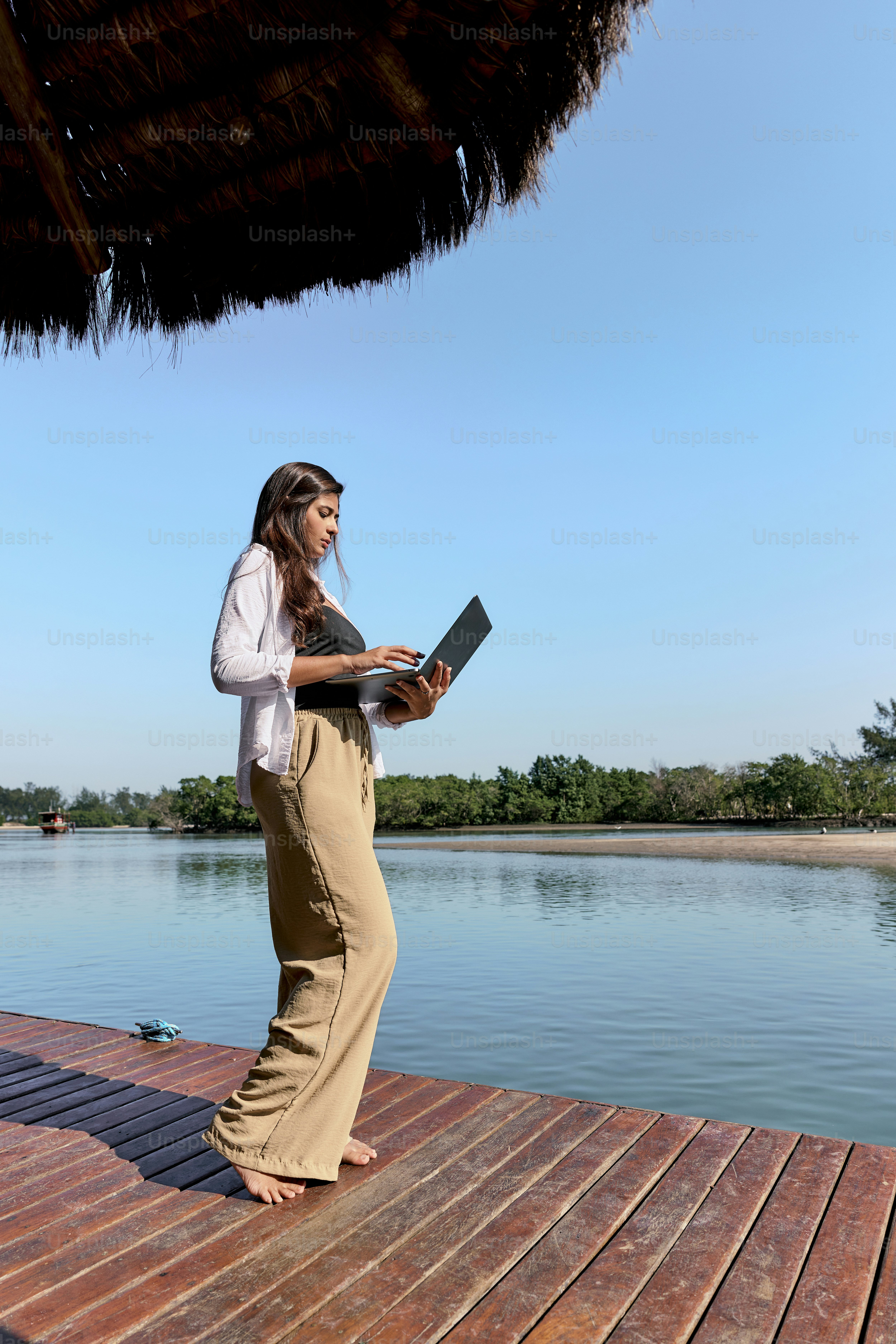 Una mujer de pie en un muelle usando una computadora portátil