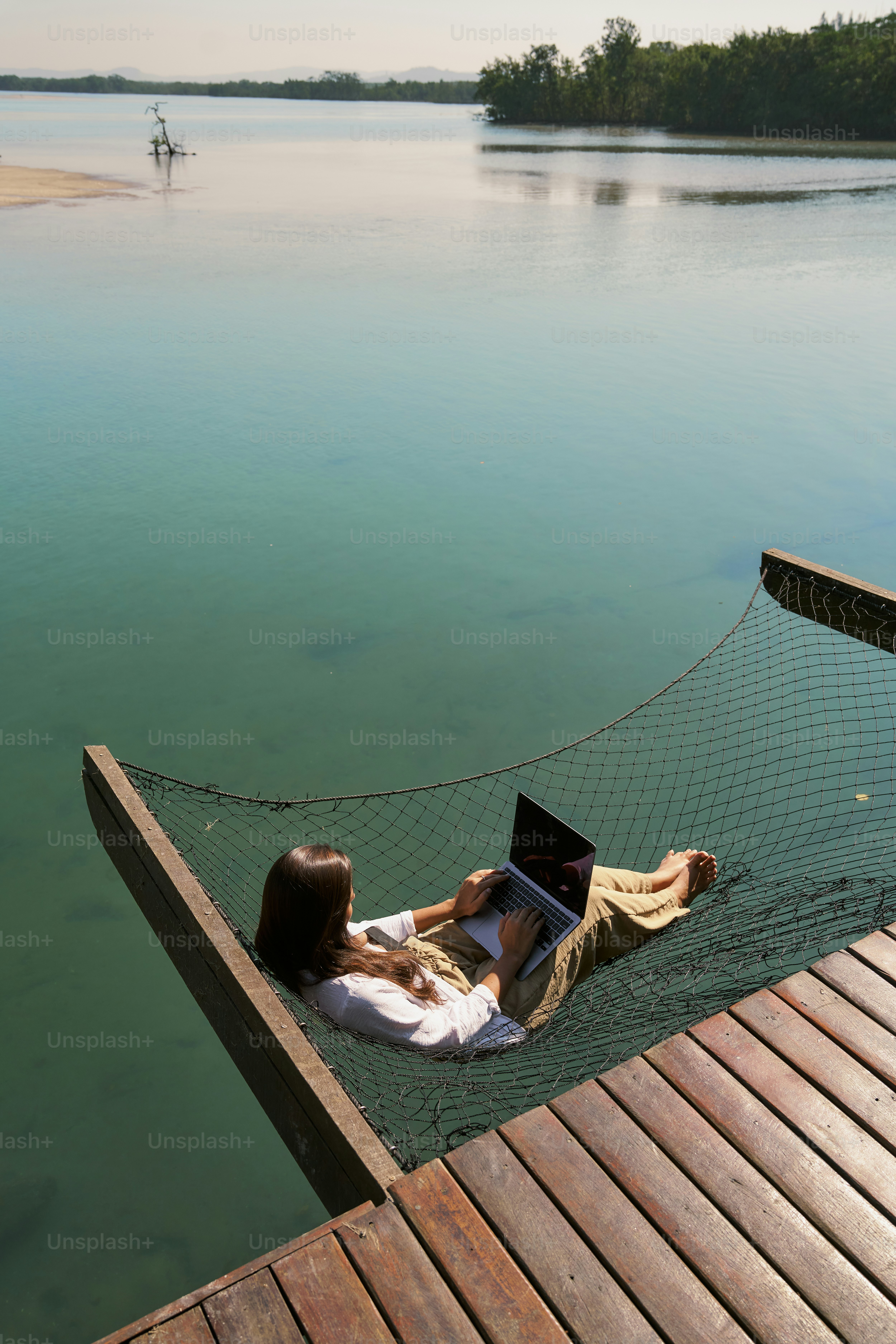 A woman laying in a hammock with a laptop on her lap