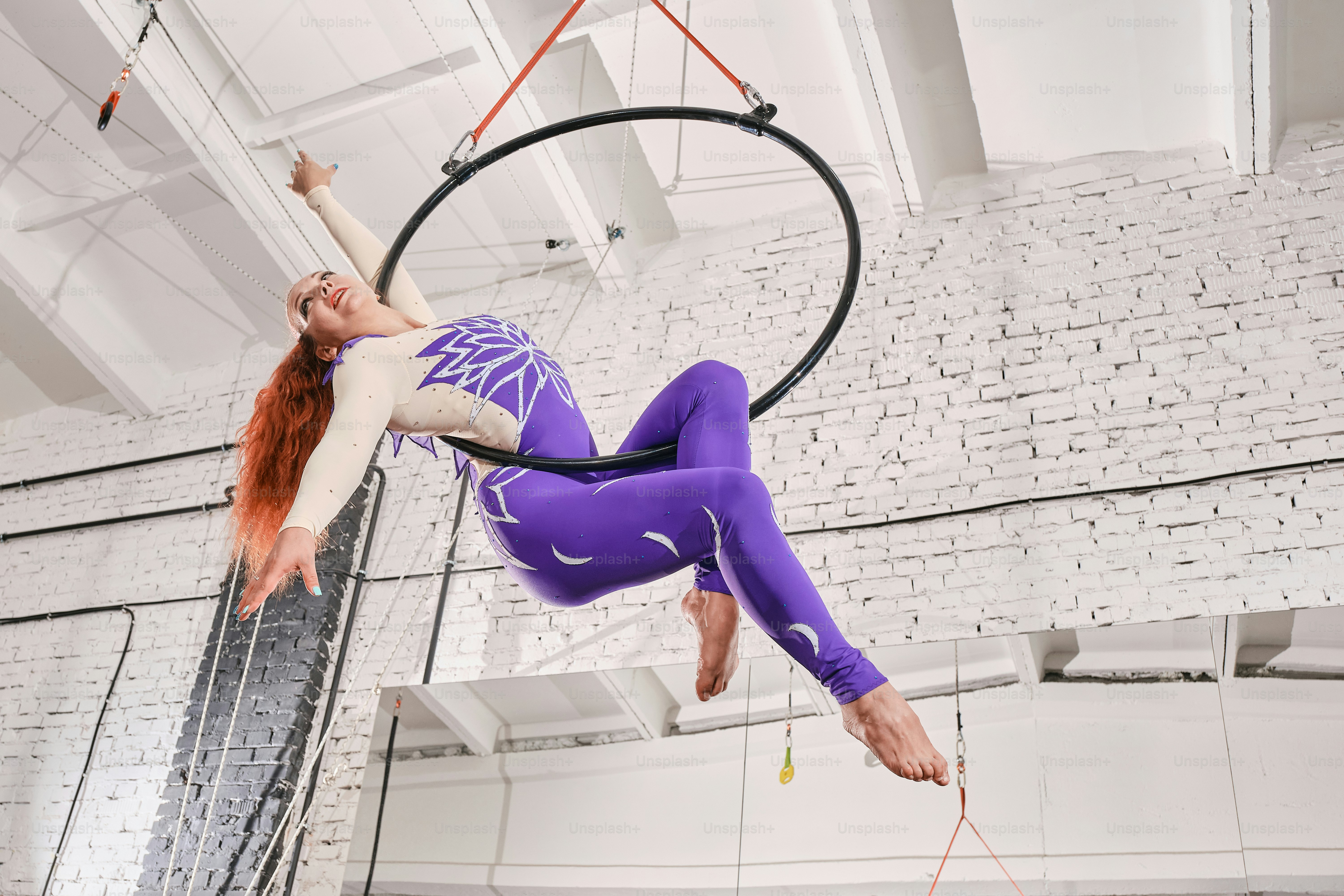 Une femme en tenue violette est suspendue à un cerceau