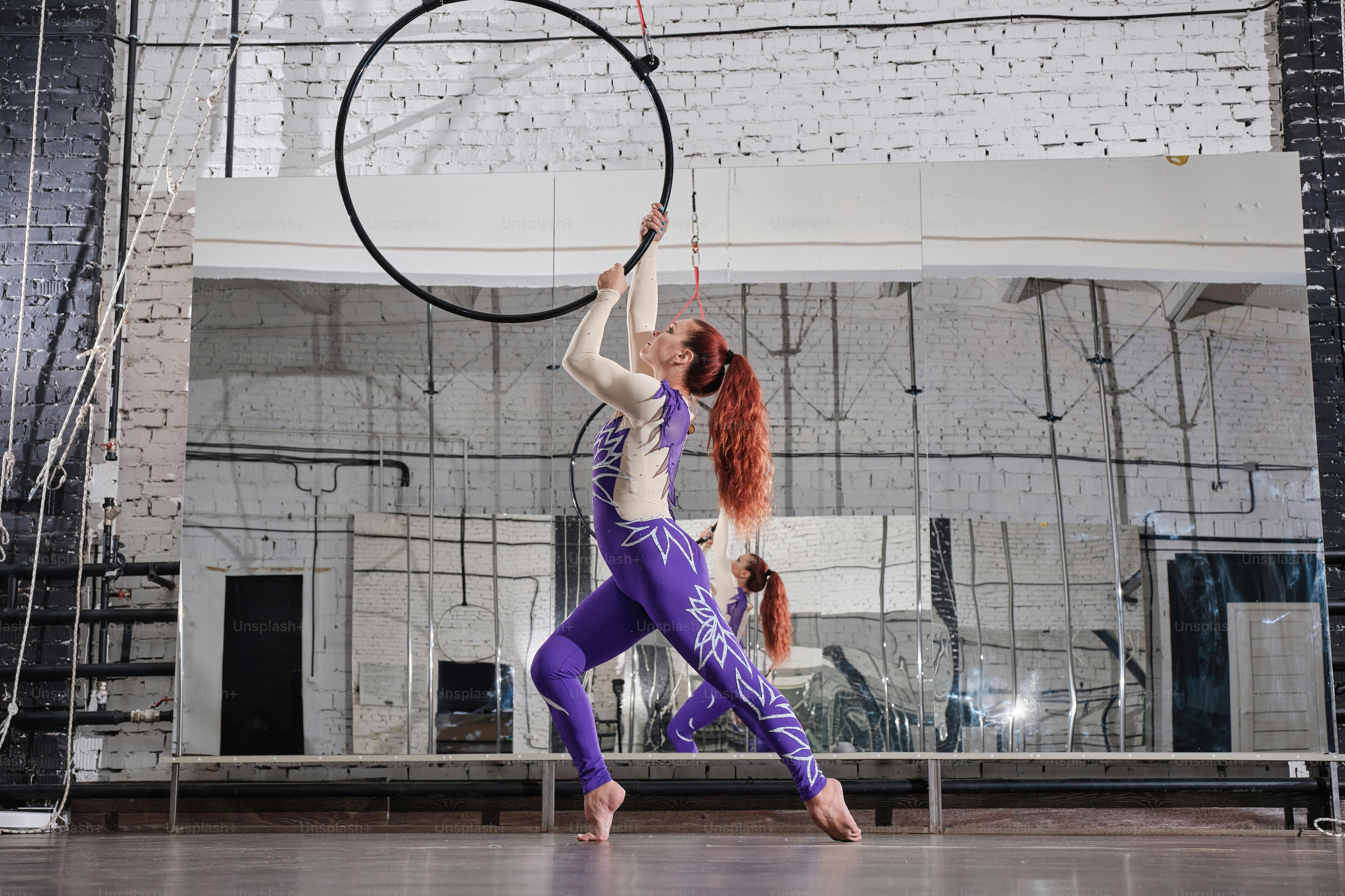 Une femme aux cheveux roux fait un tour avec un cerceau