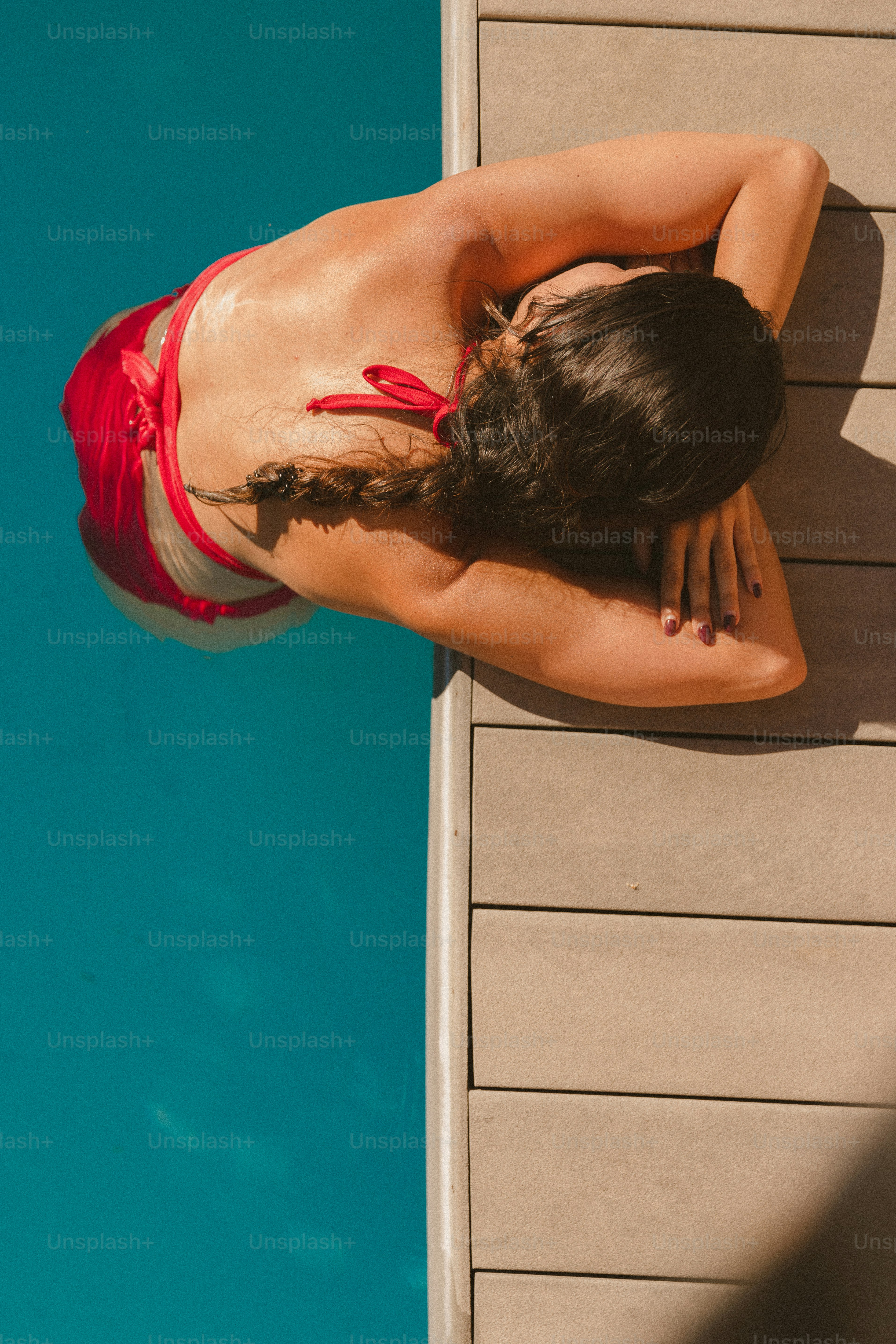 A woman in a red bikini standing next to a swimming pool