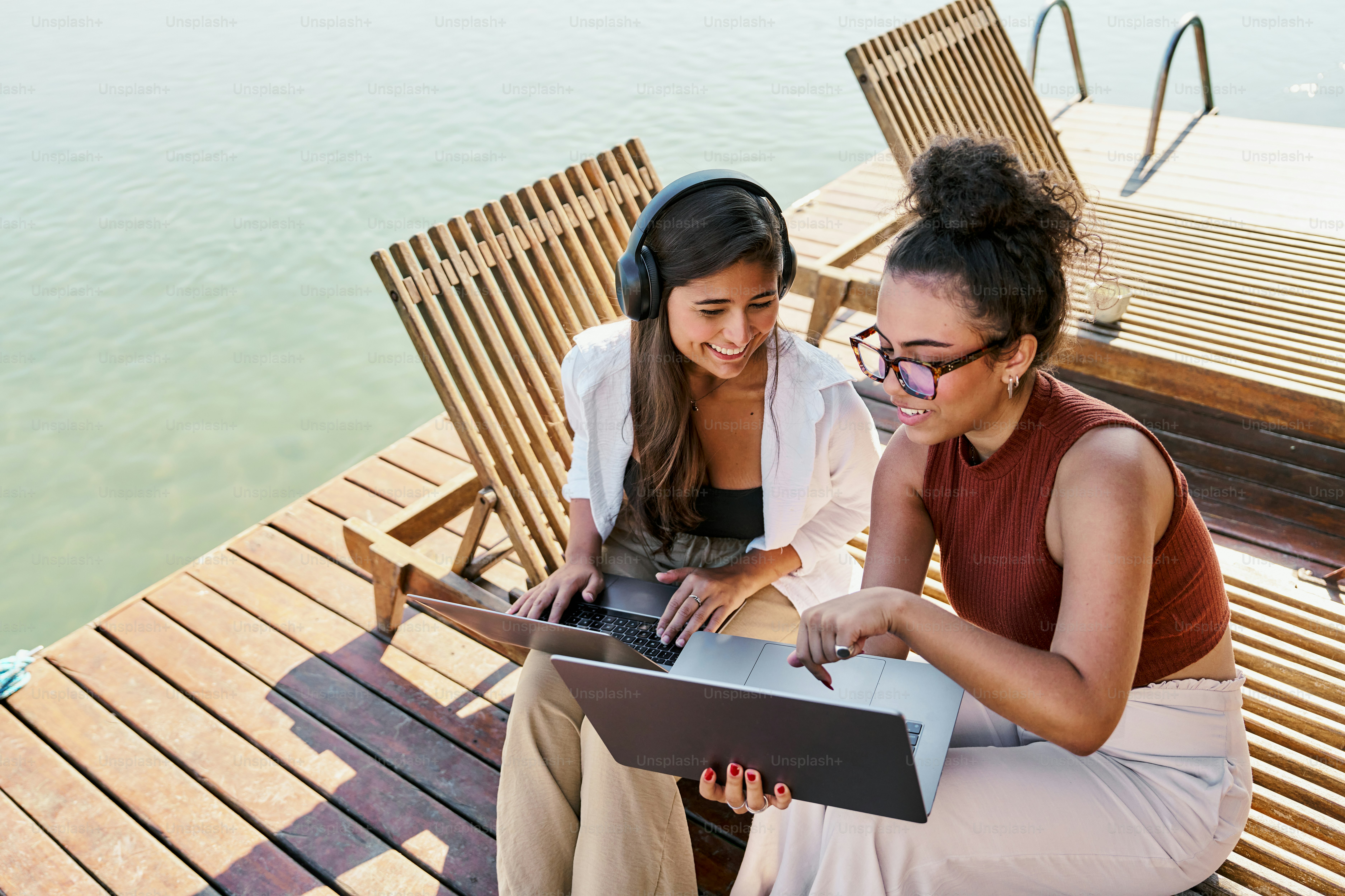 A couple of women sitting on top of a wooden deck