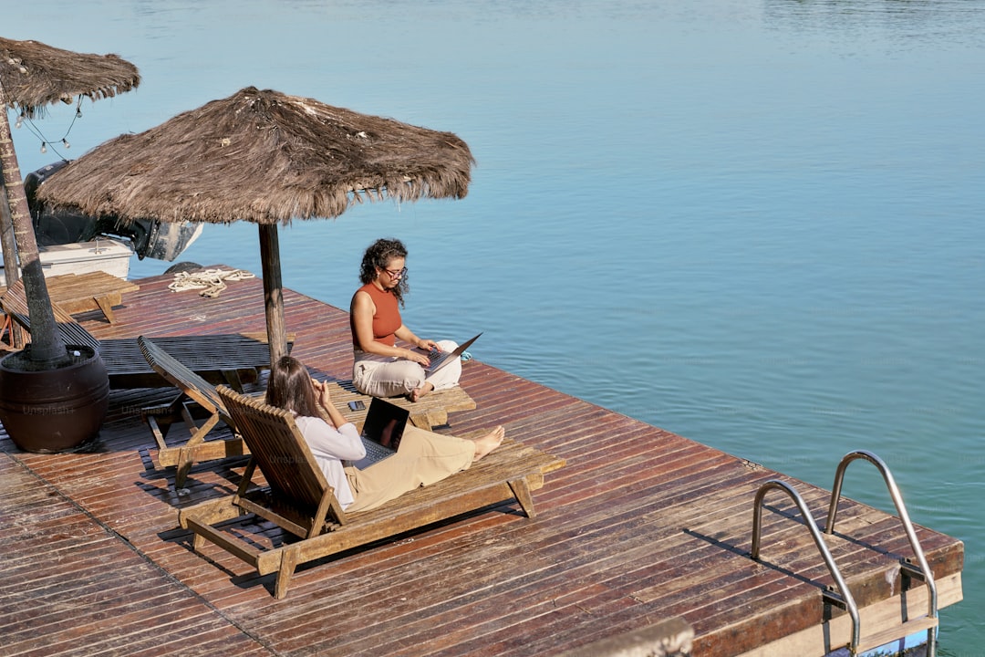 A woman sitting on a lounge chair next to a body of water