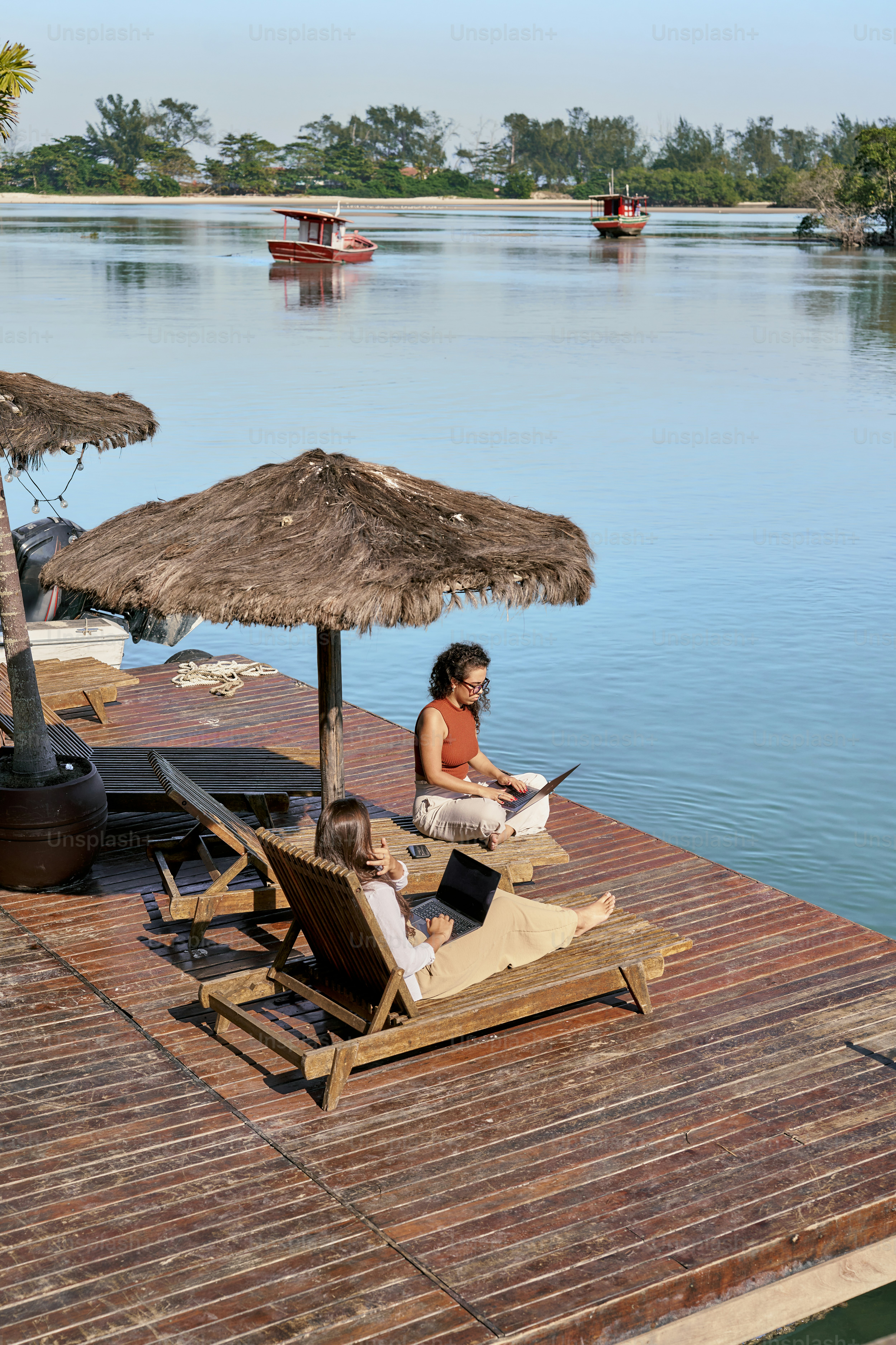 A woman sitting on a deck next to a body of water