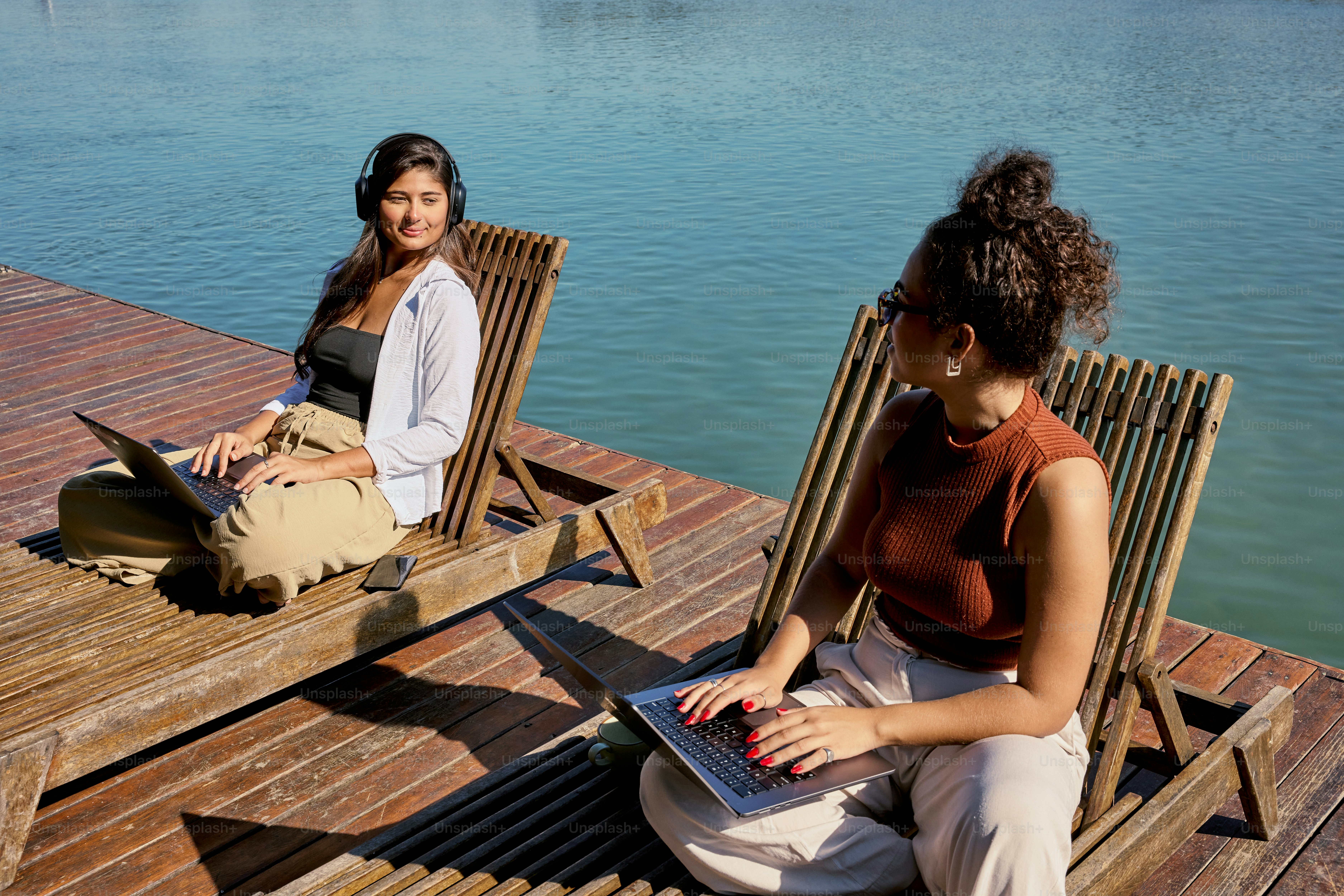 A couple of women sitting on top of a wooden dock