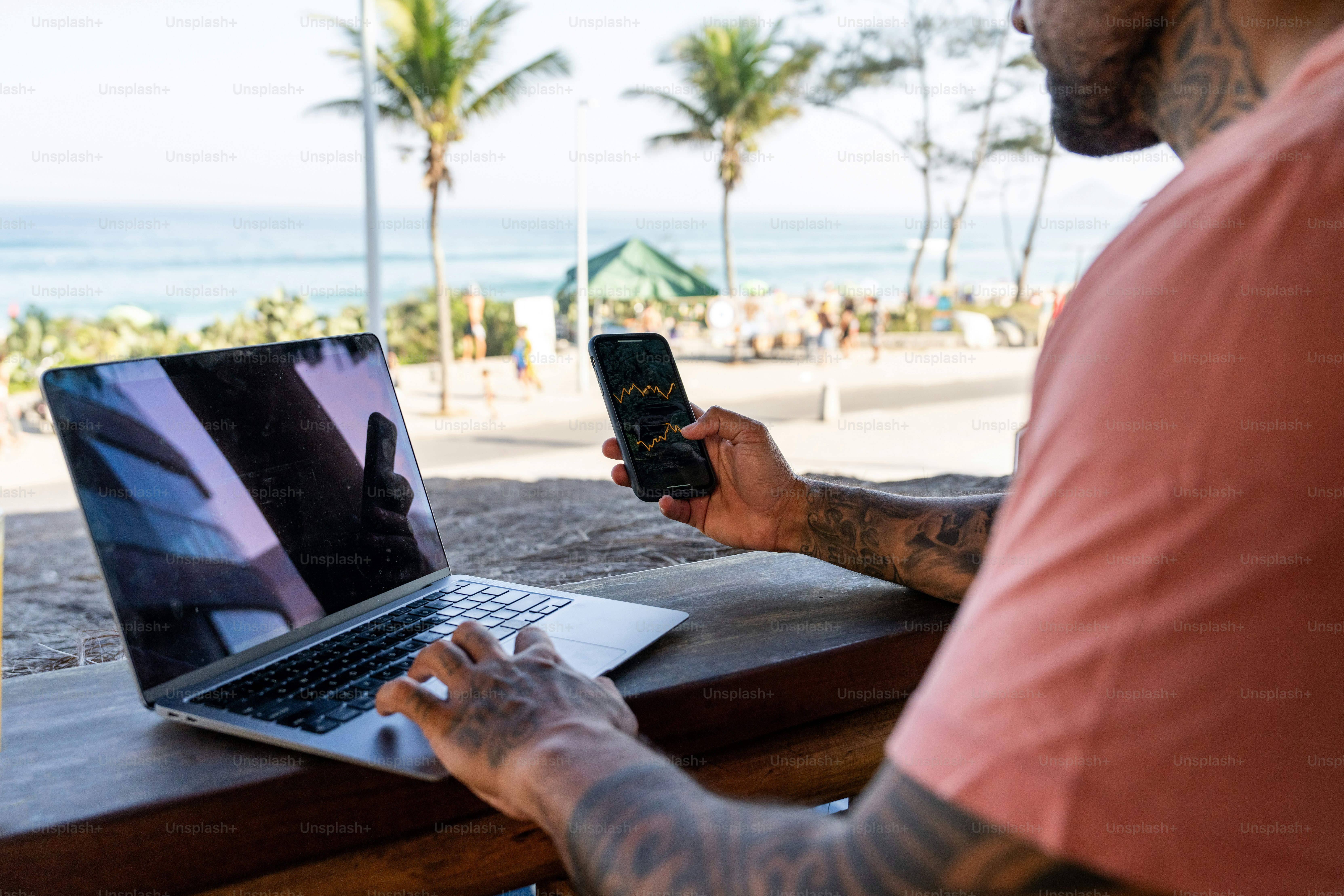 A man sitting at a table with a laptop and cell phone