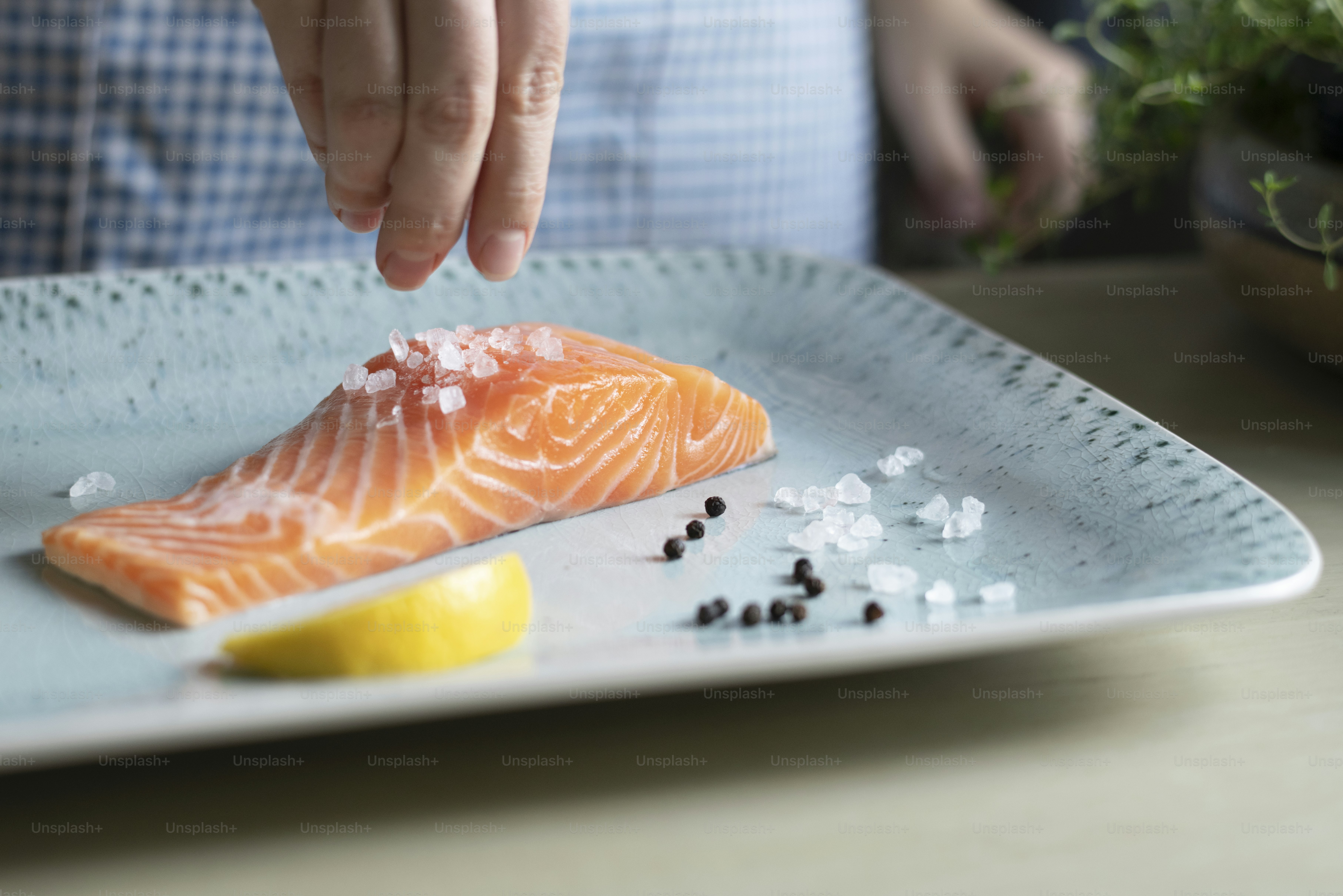 A person seasoning a fillet of salmon food photography recipe idea