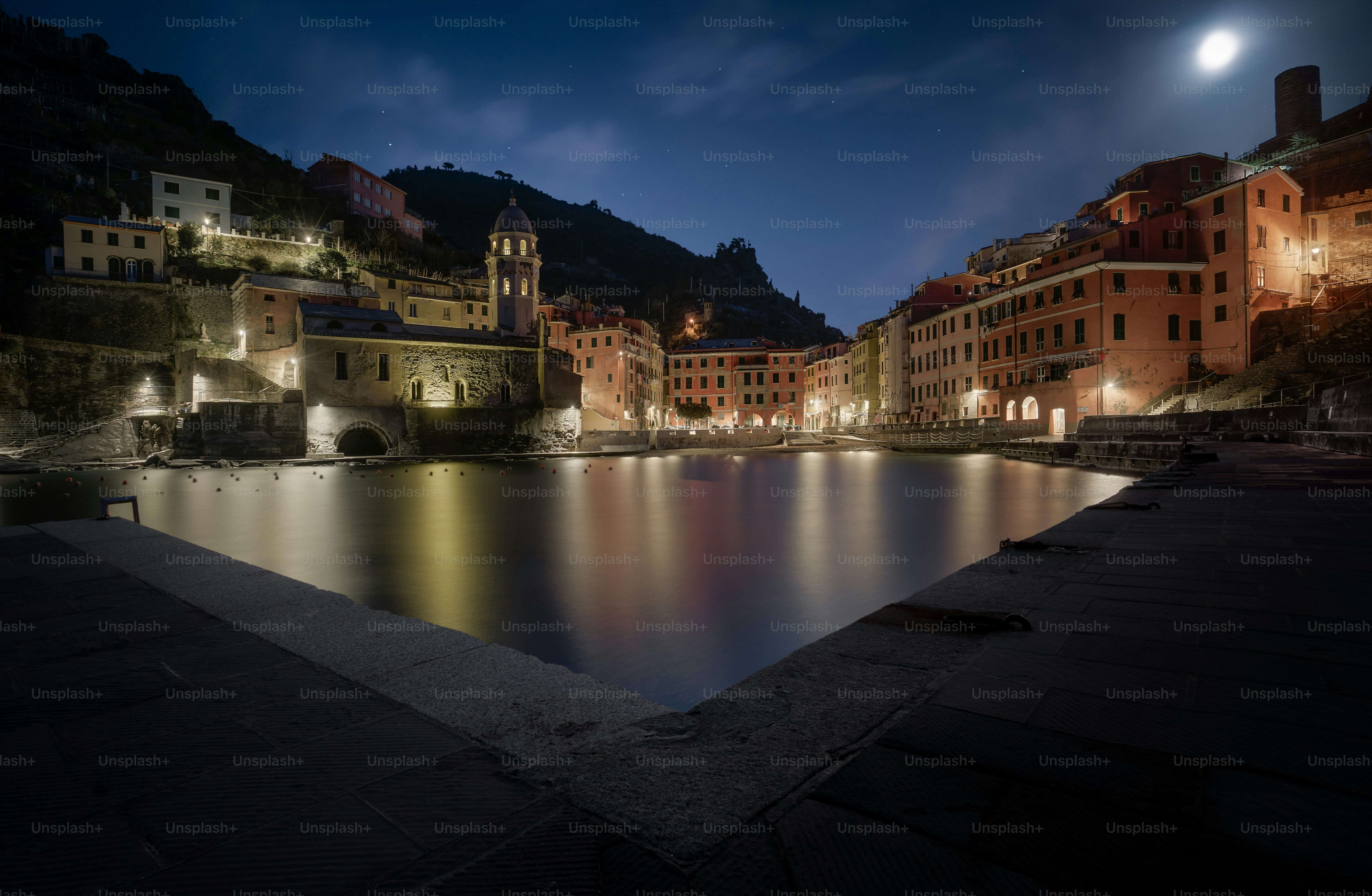 A night view of a town with a lake and mountains in the background