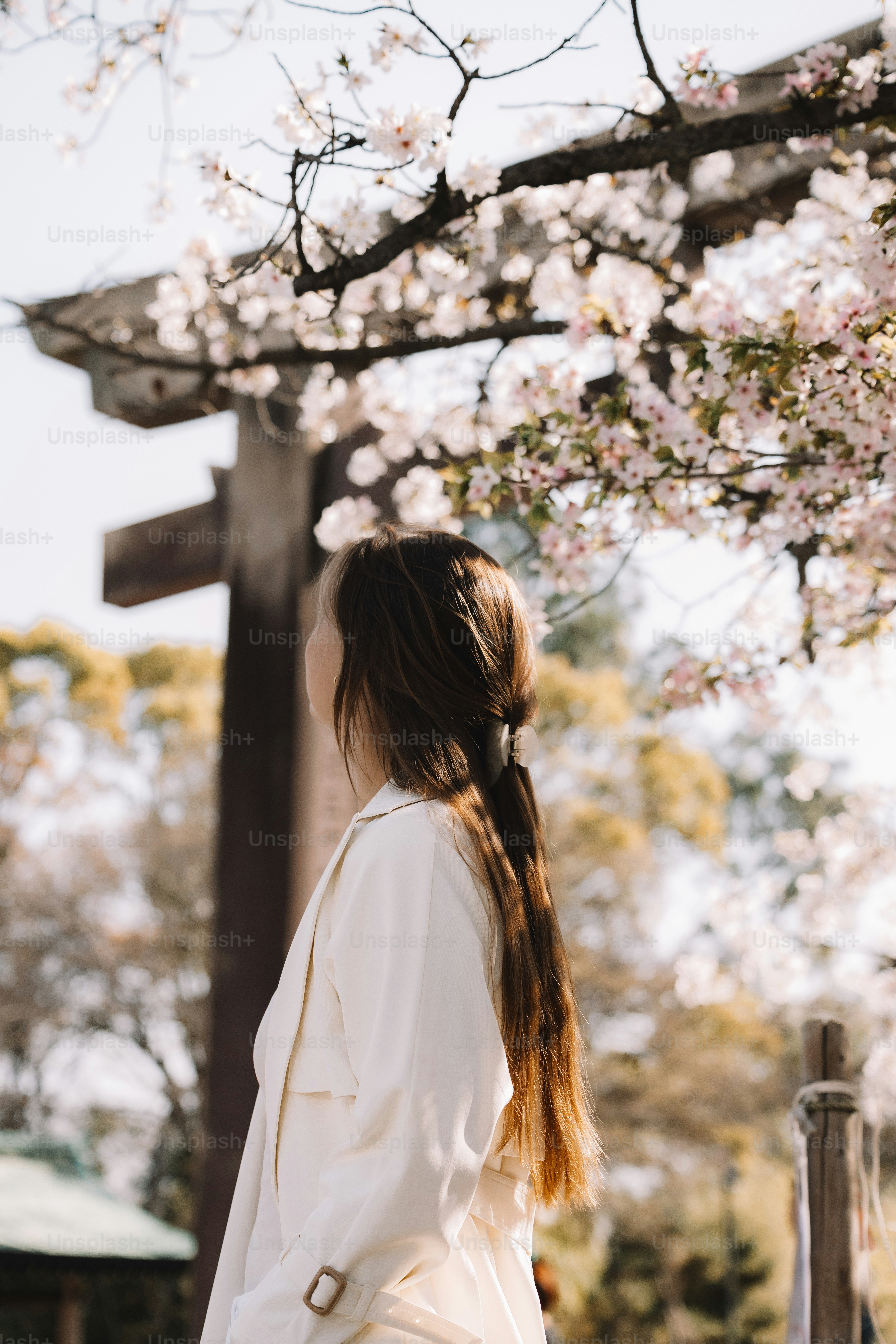 A woman standing under a cherry blossom tree