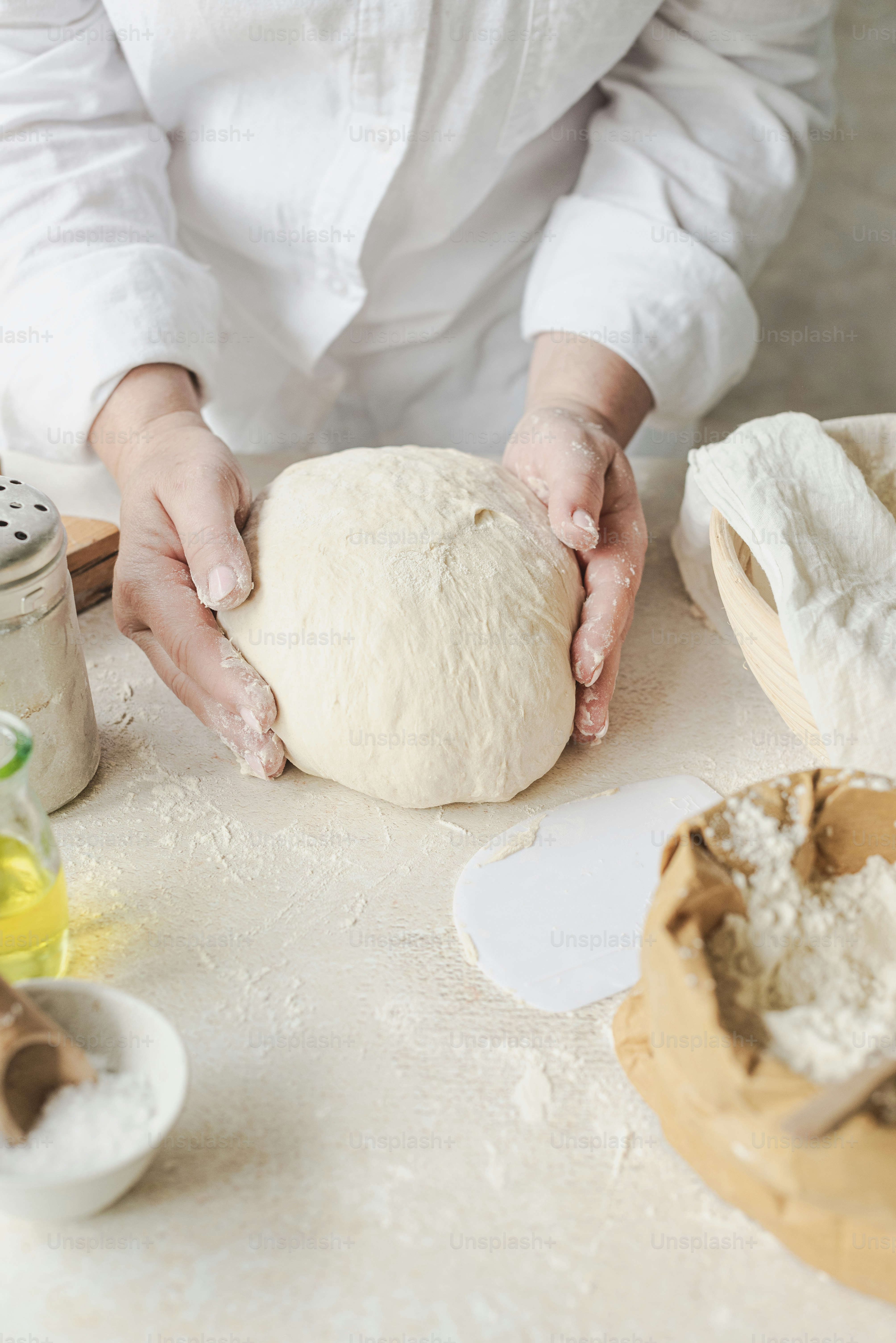 A person kneading a ball of bread on top of a table