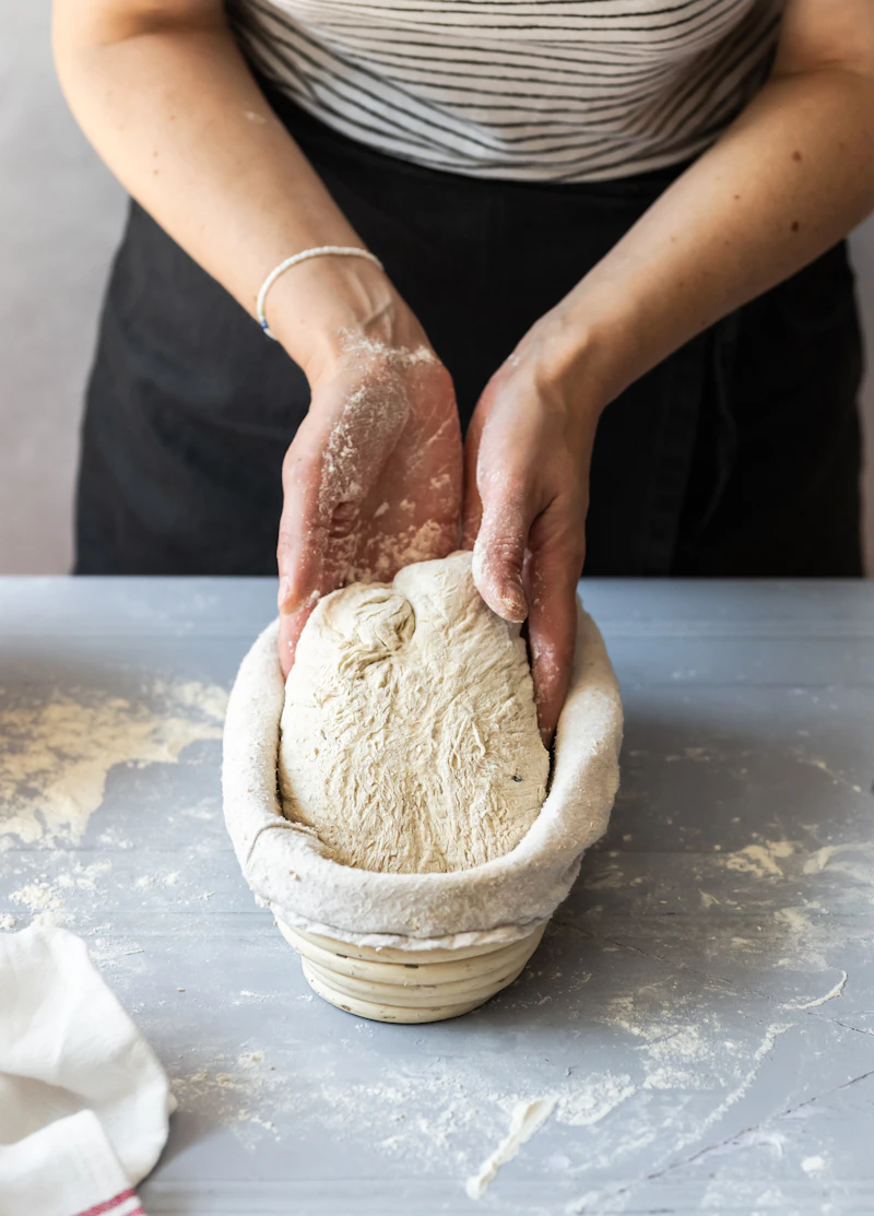 Hands kneading and folding sourdough dough in a bowl during bulk fermentation