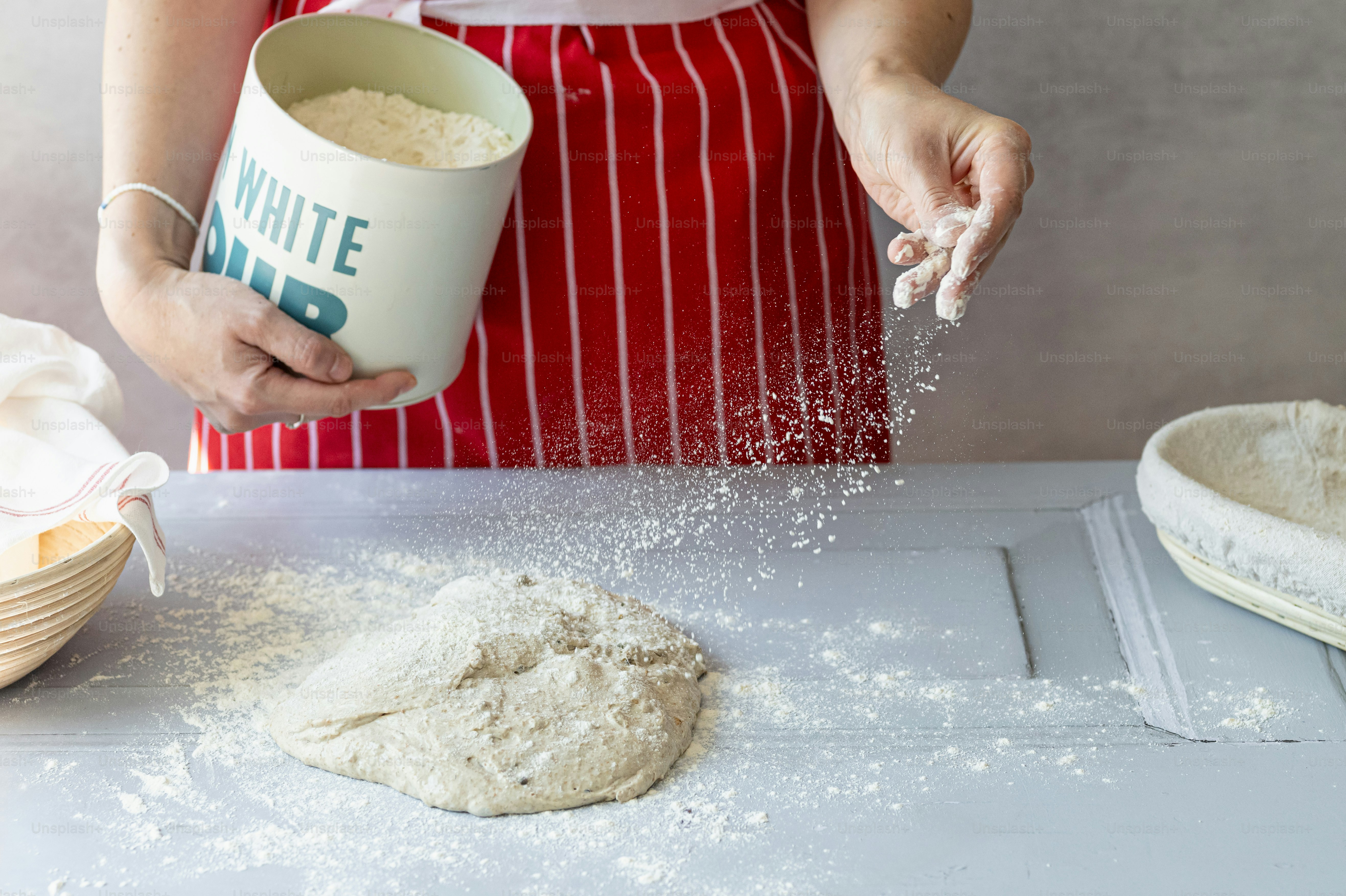 A woman in a red apron is pouring flour into a cup