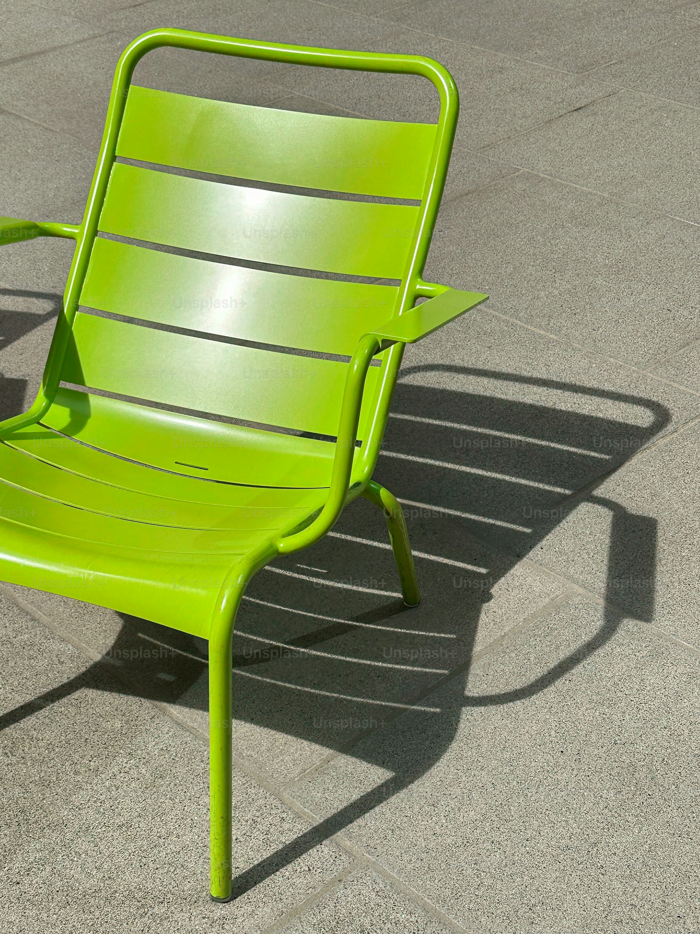 A green chair sitting on top of a sidewalk