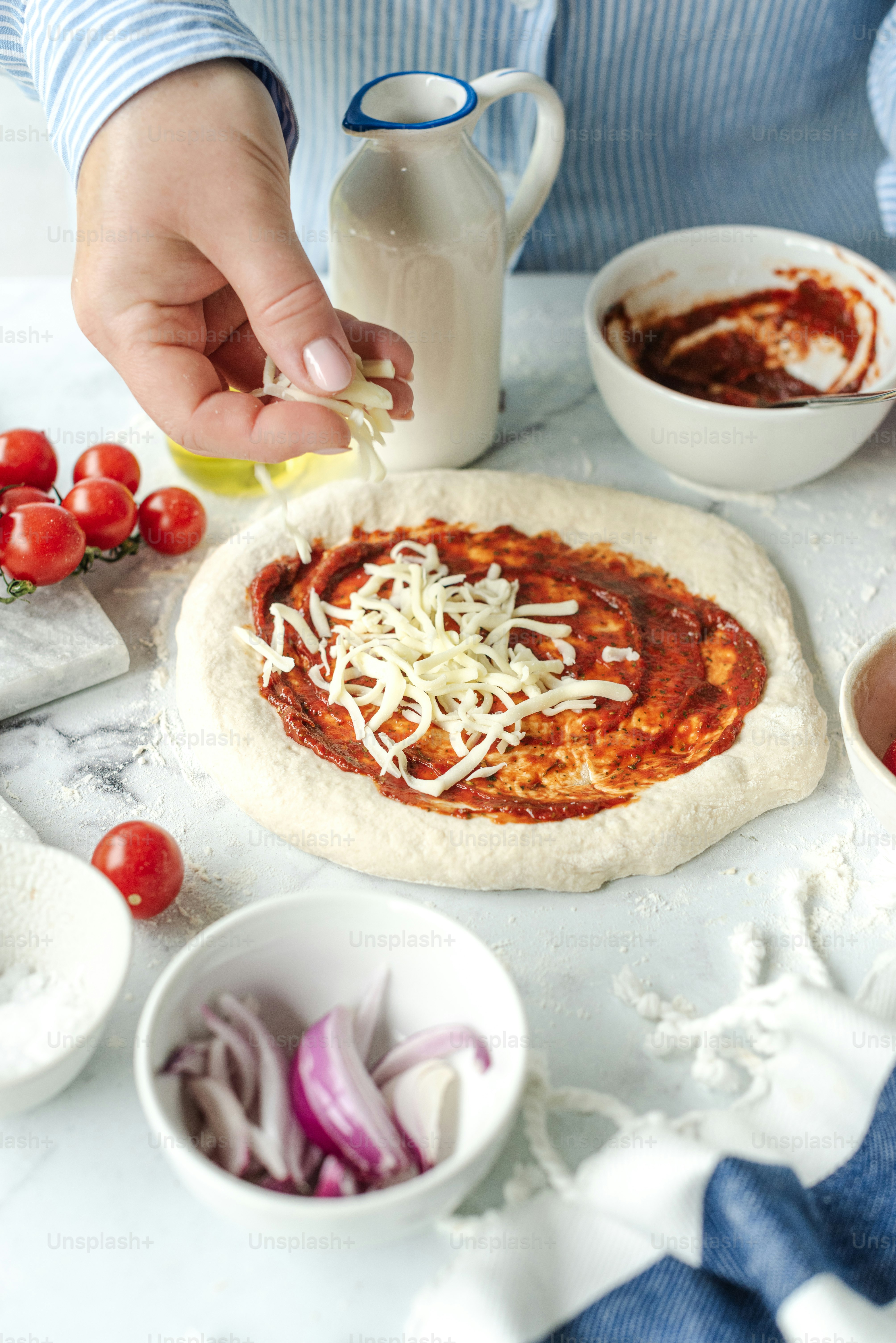 A person making a homemade pizza on a table