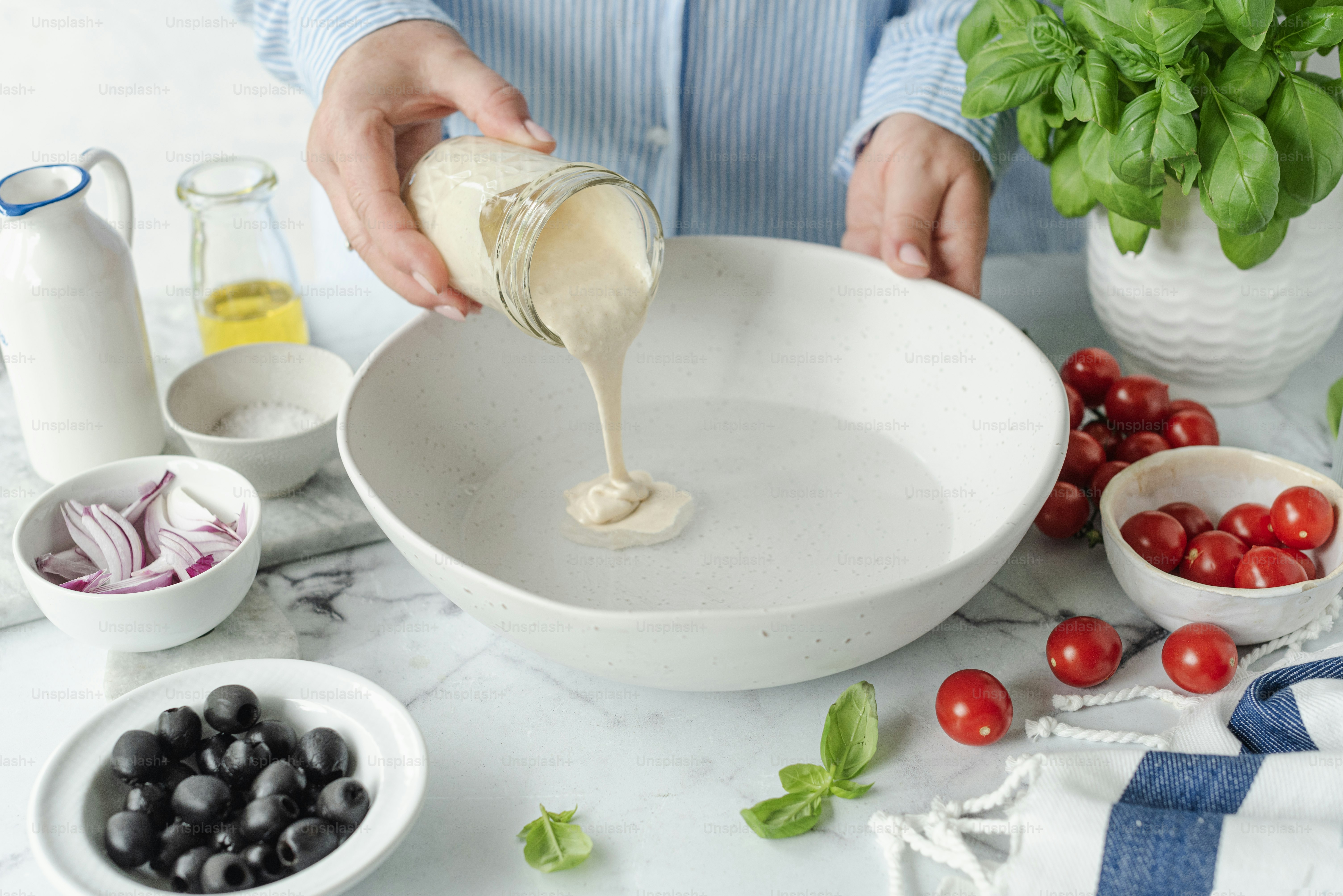 A person pouring dressing into a white bowl