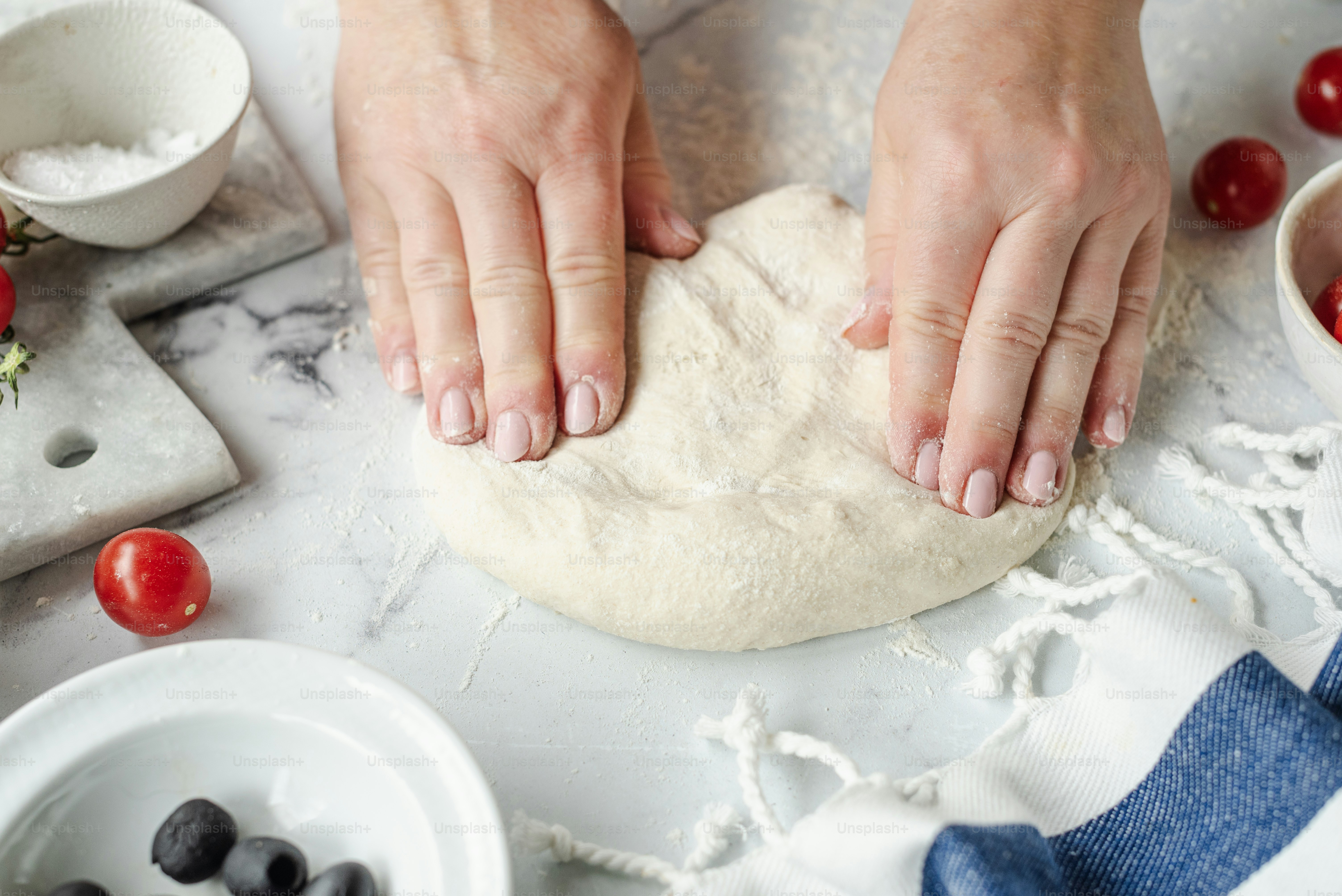 A person kneading dough on top of a table