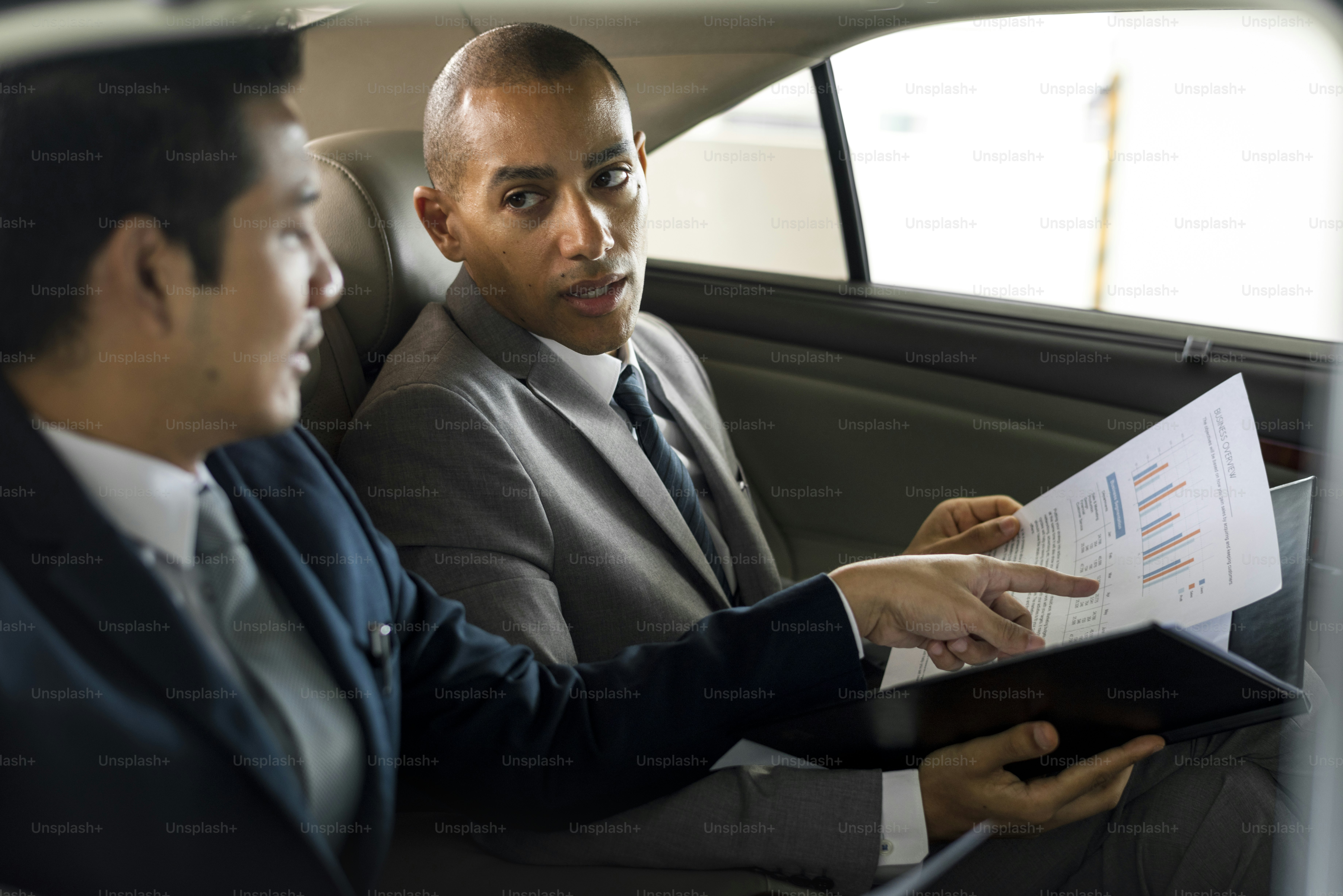 Des hommes d’affaires parlent d’un rapport à l’intérieur de la voiture