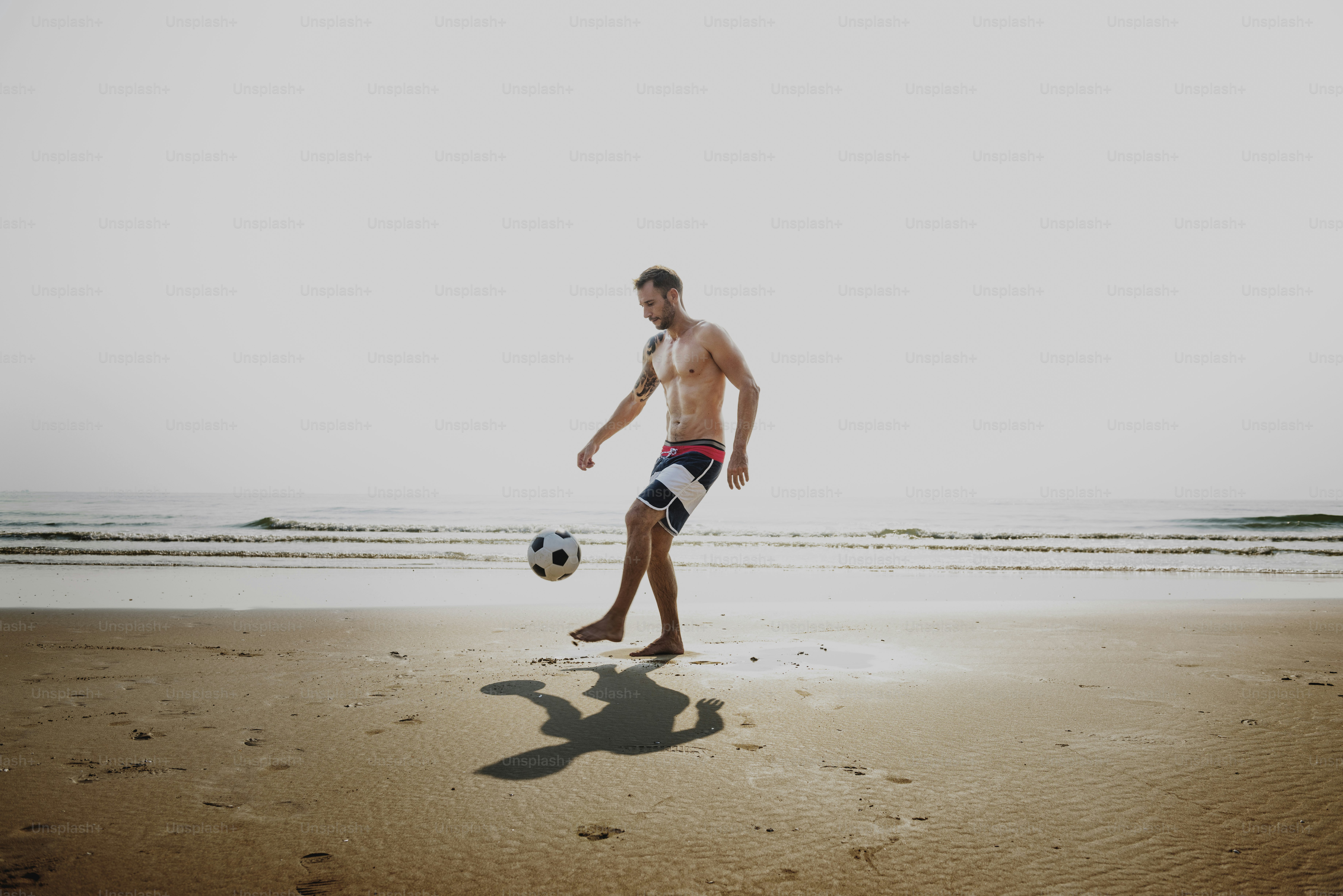 bell'uomo che gioca a calcio concetto di spiaggia
