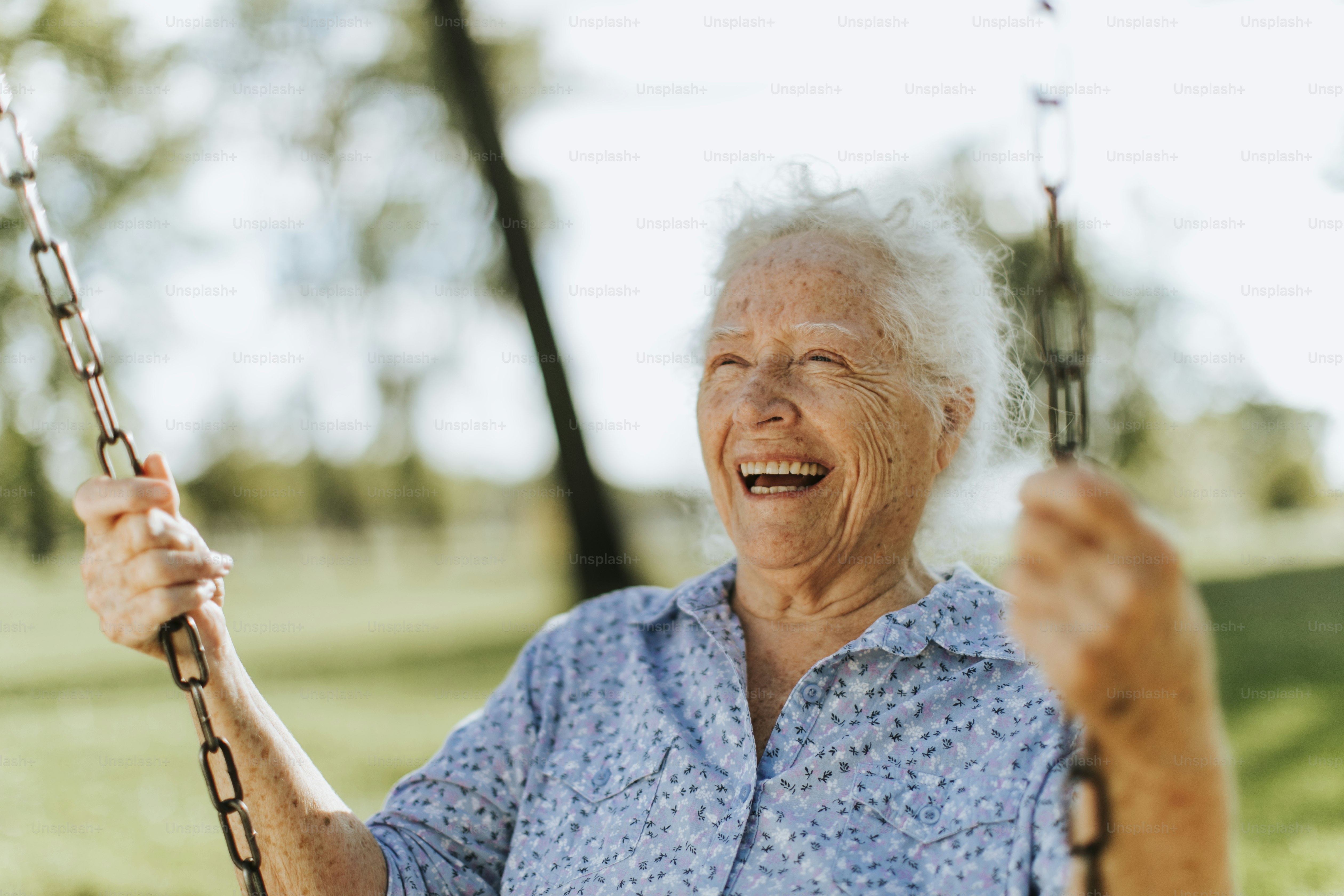Fröhliche Seniorin auf einer Schaukel auf einem Spielplatz