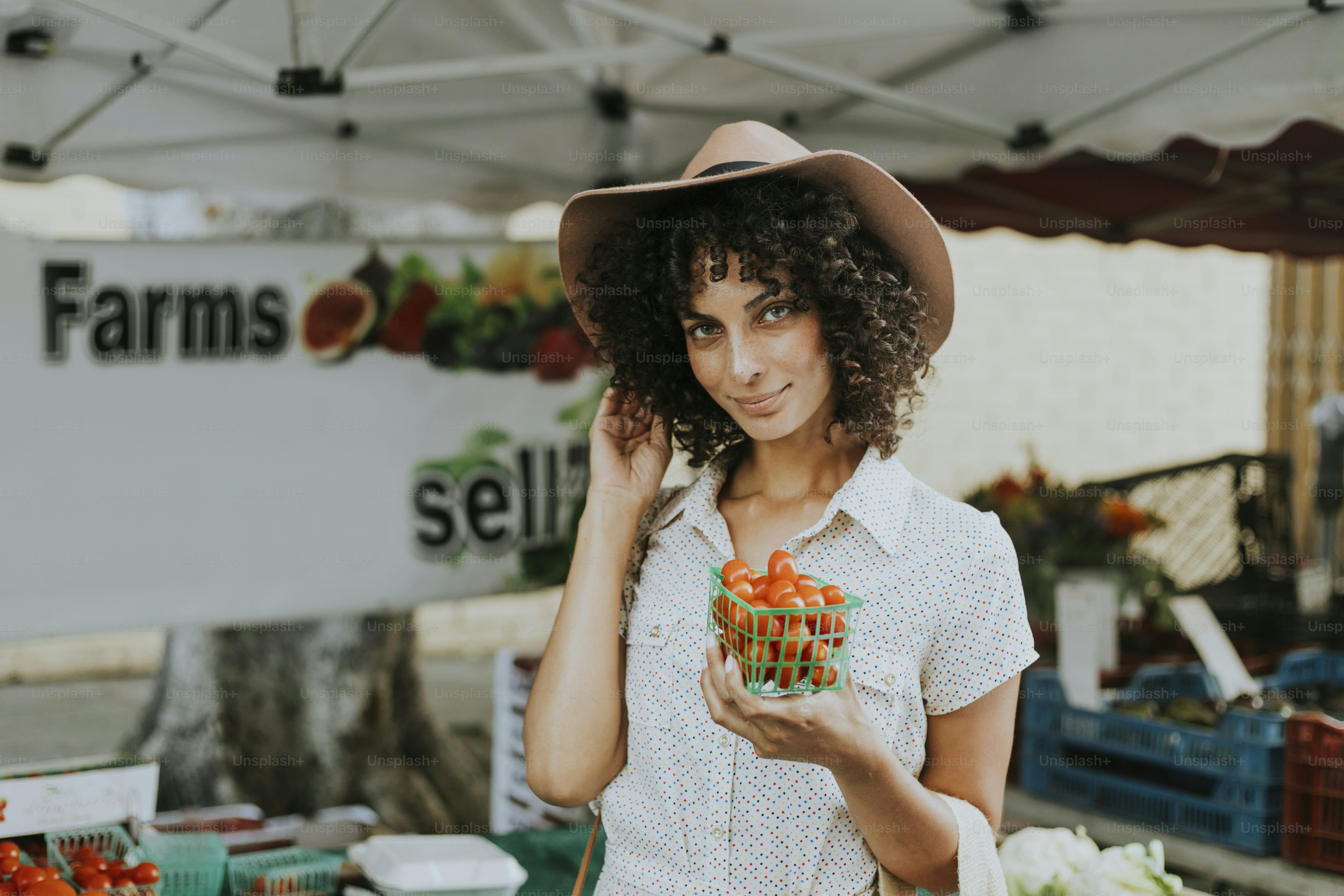Schöne Frau, die Tomaten auf einem Bauernmarkt kauft