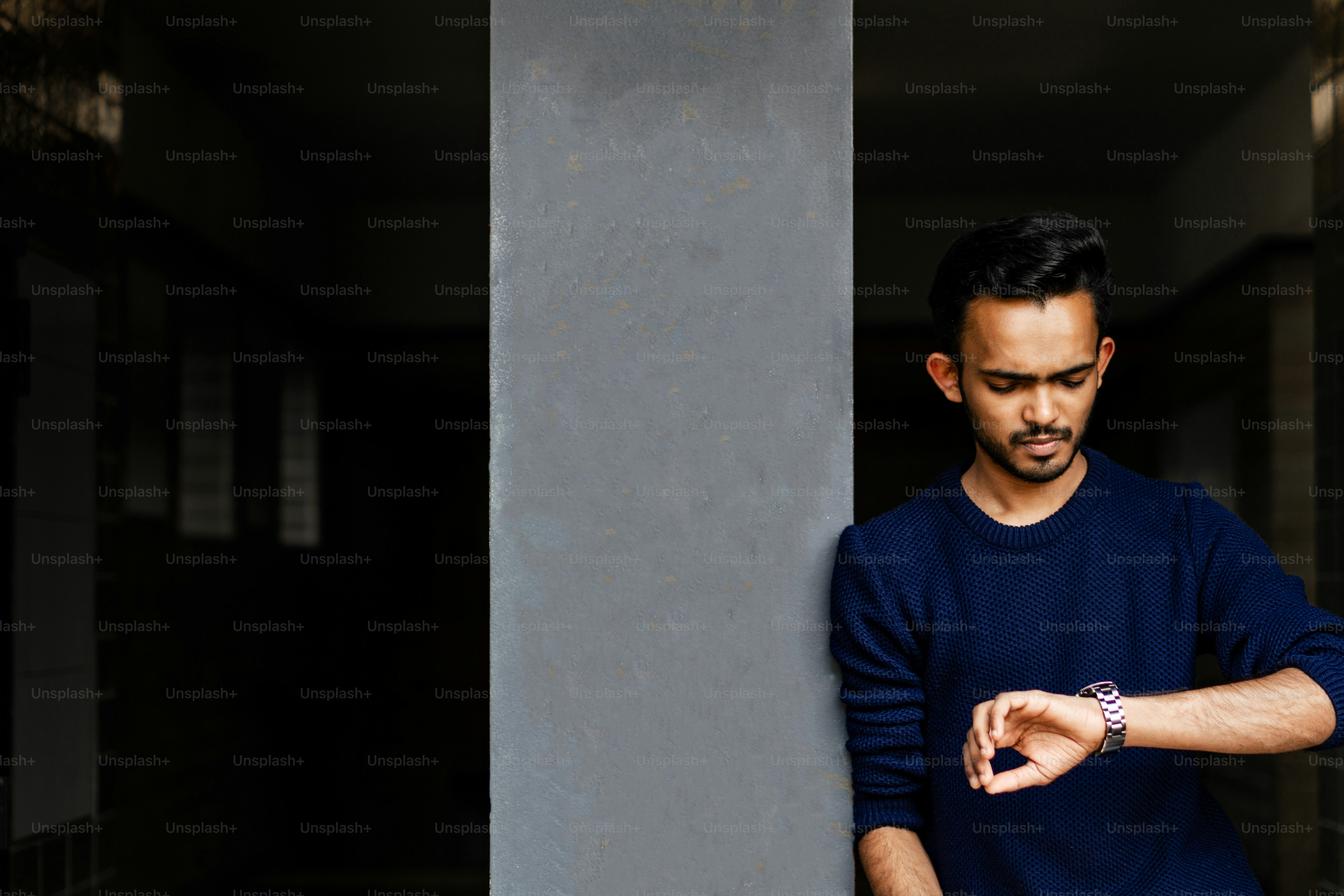 A man in a blue shirt leaning against a pillar