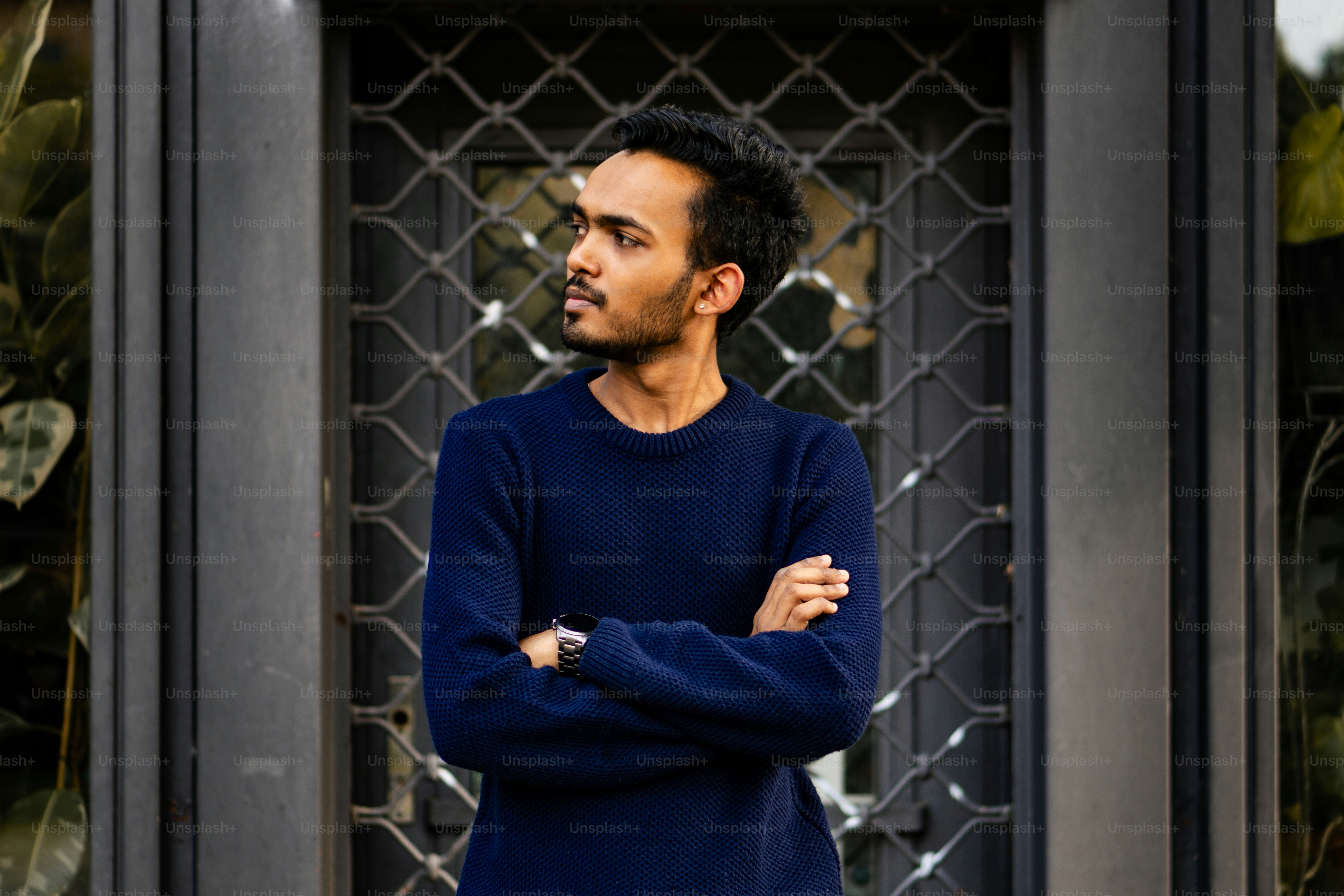 A man standing in front of a gate with his arms crossed